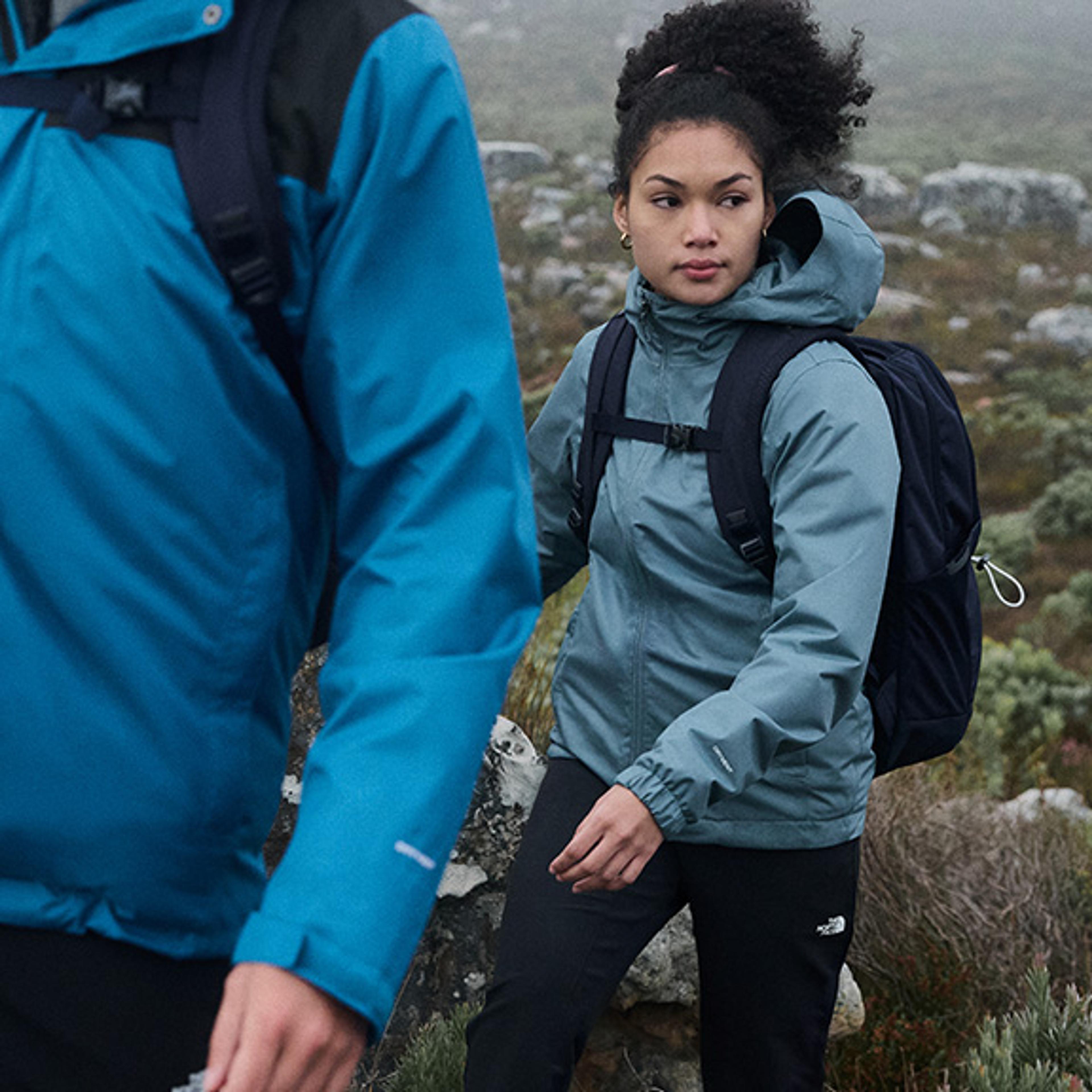 a man and a woman are hiking up a hill .