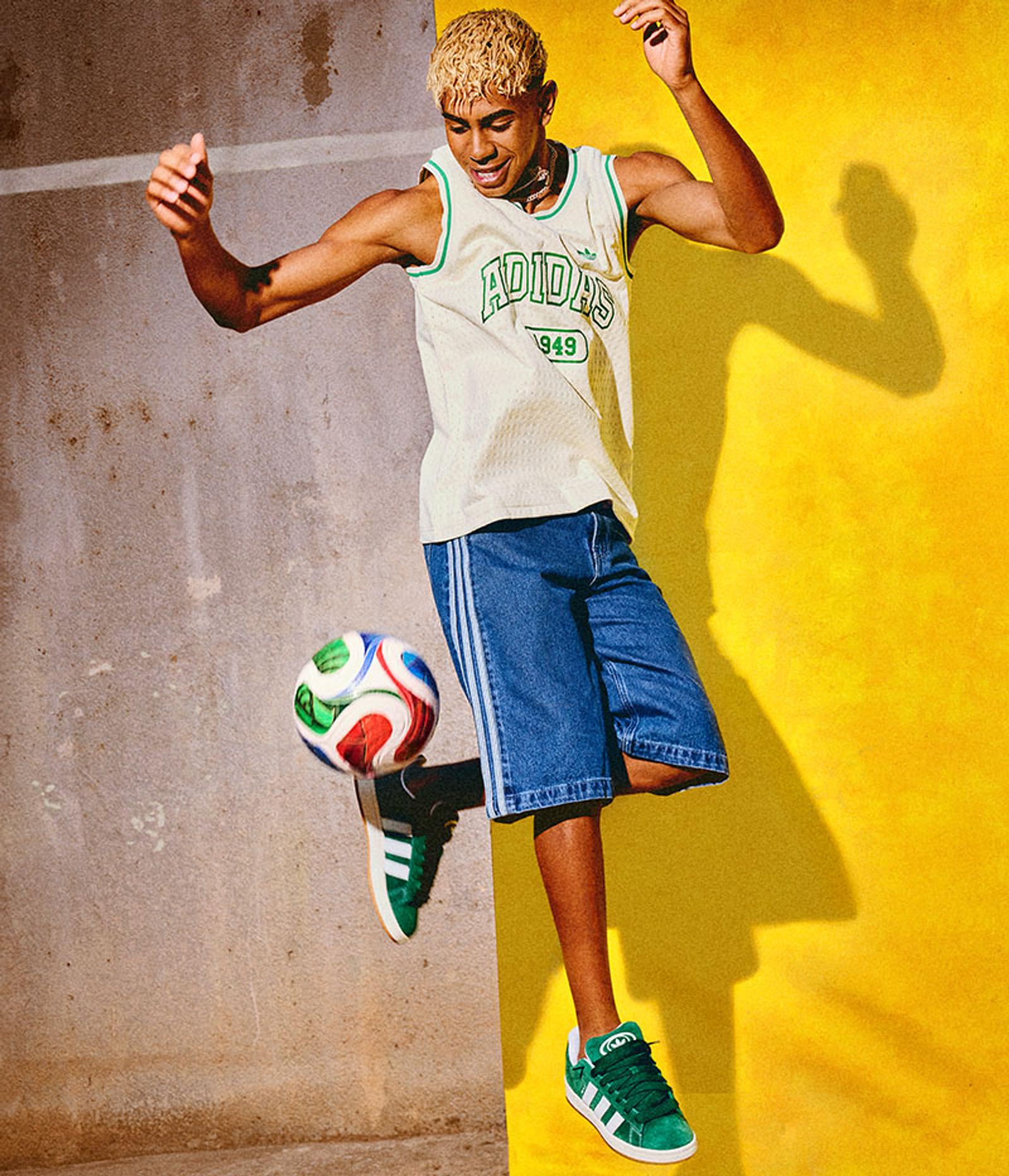 a man in an adidas jersey is kicking a soccer ball