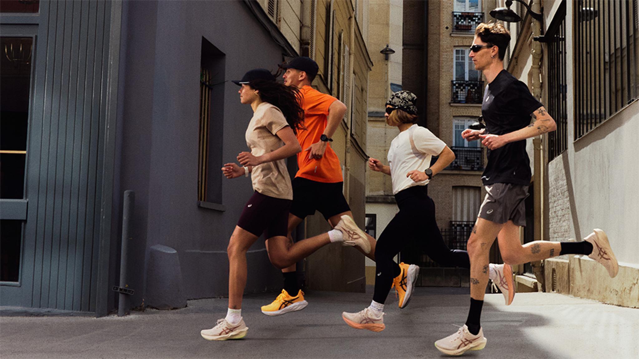 Four people in athletic wear running down an urban street.