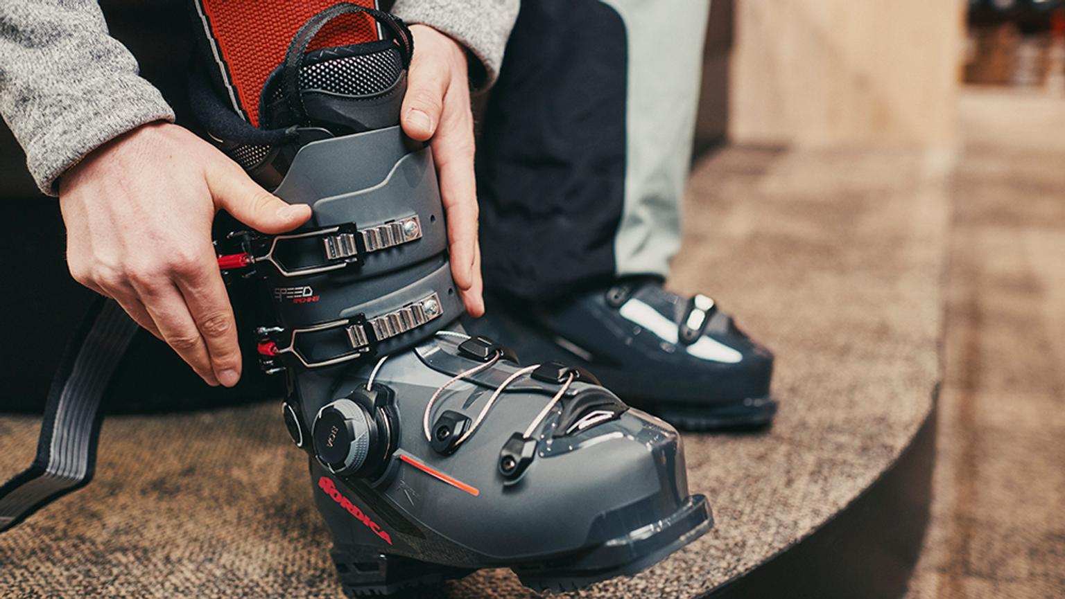 a person is putting on a pair of ski boots .
