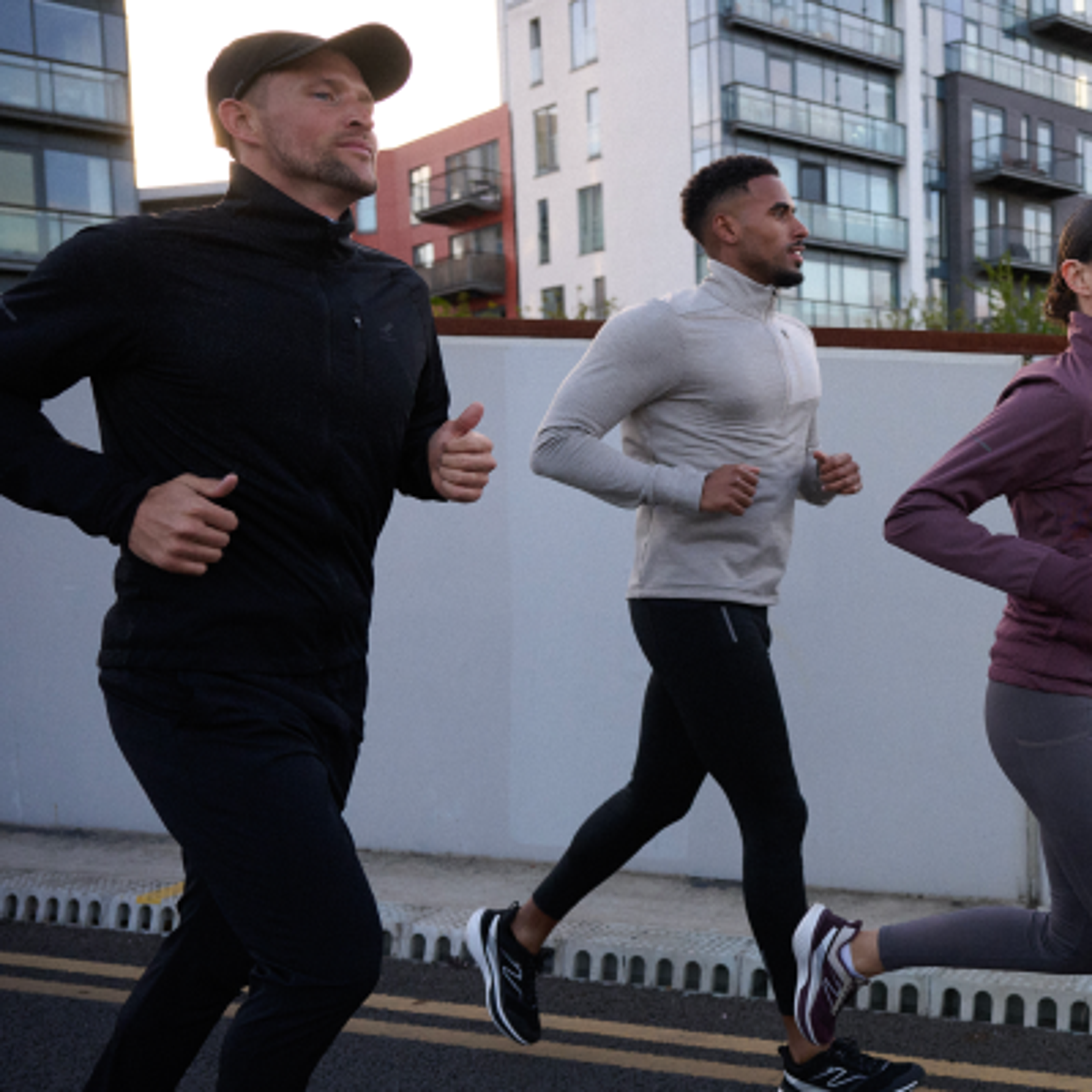 Three people jogging outdoors in athletic wear.