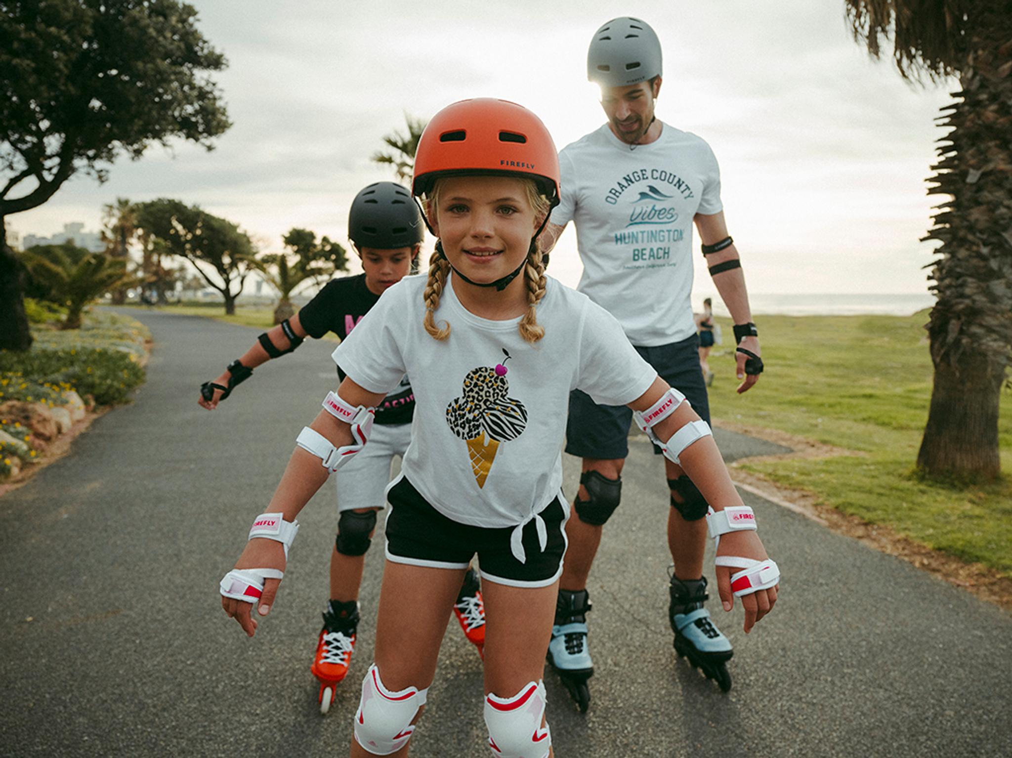 En vuxen och två barn åker inlines och sparkcykel