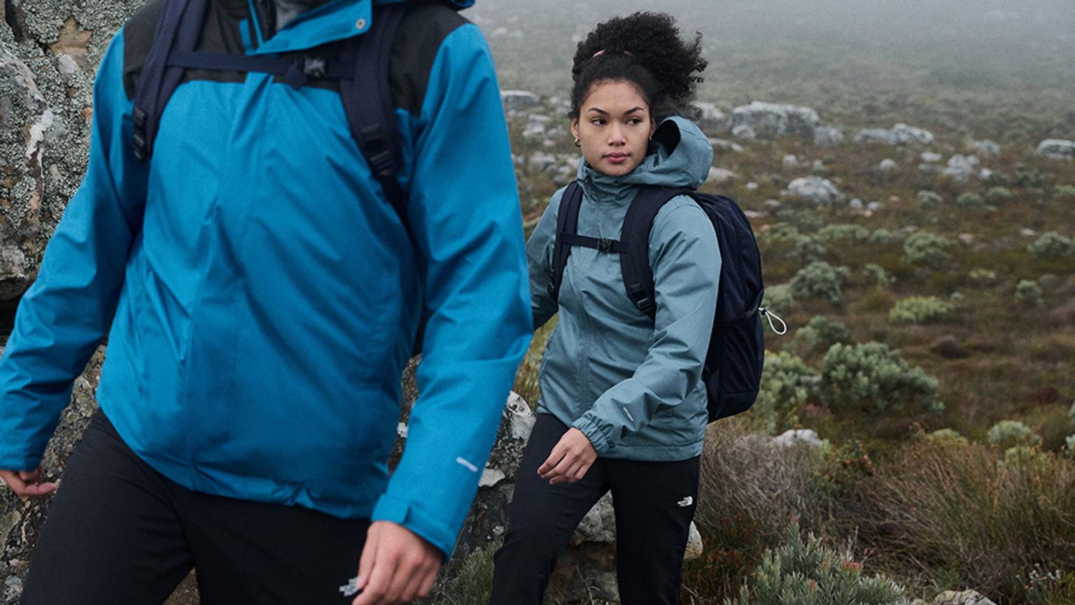 a man and a woman are hiking up a hill .