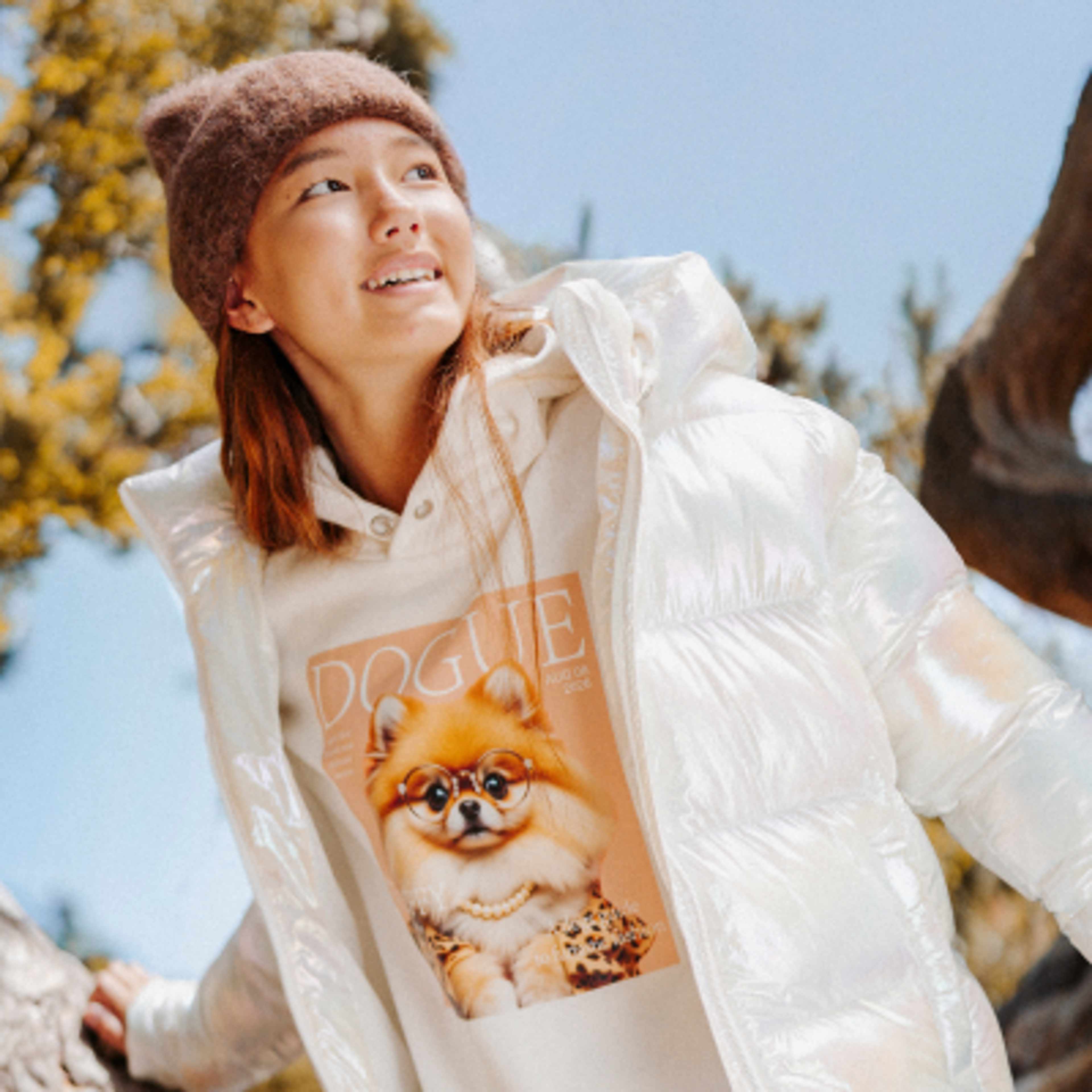 A young girl in a blue jacket walks her fluffy brown dog on a beachside path.