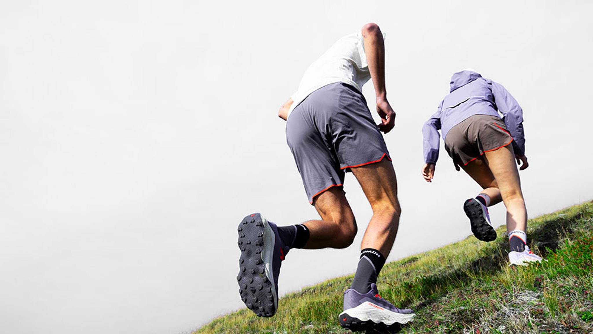 a man and a woman are running up a grassy hill .