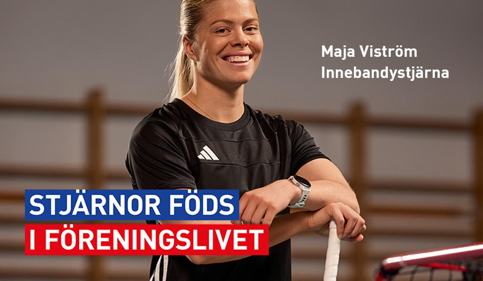 a woman in a black shirt is holding a hockey stick and smiling .