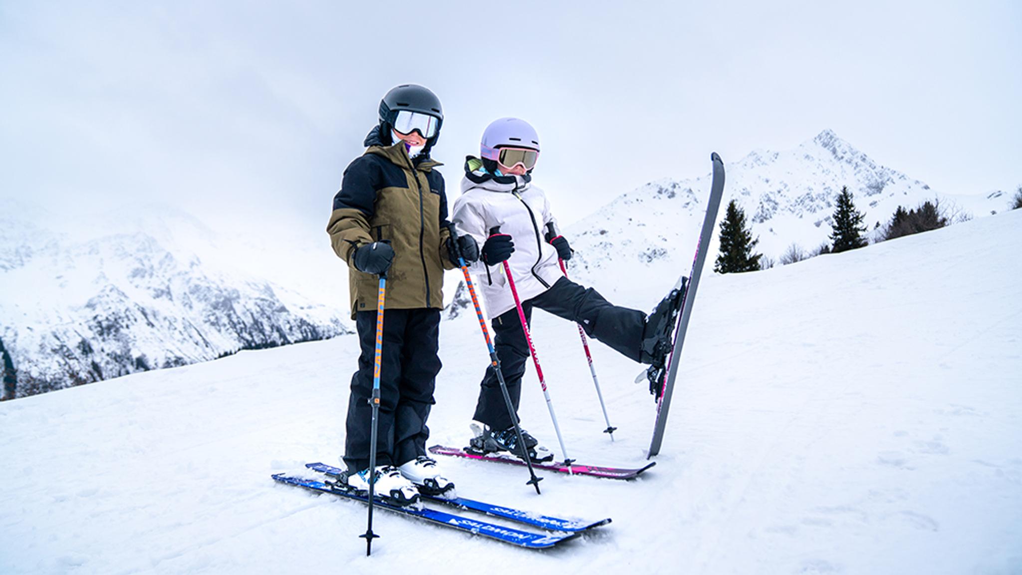a boy and a girl are standing next to each other on skis in the snow .