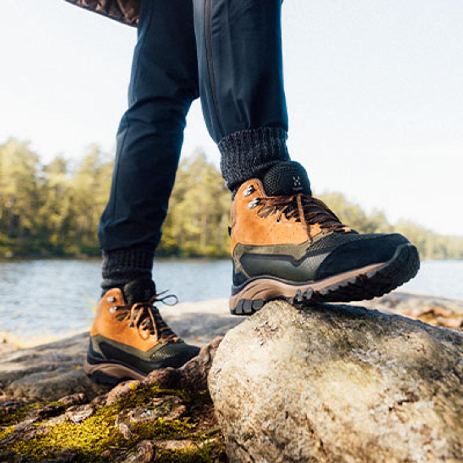 a person is standing on a rock wearing hiking boots .