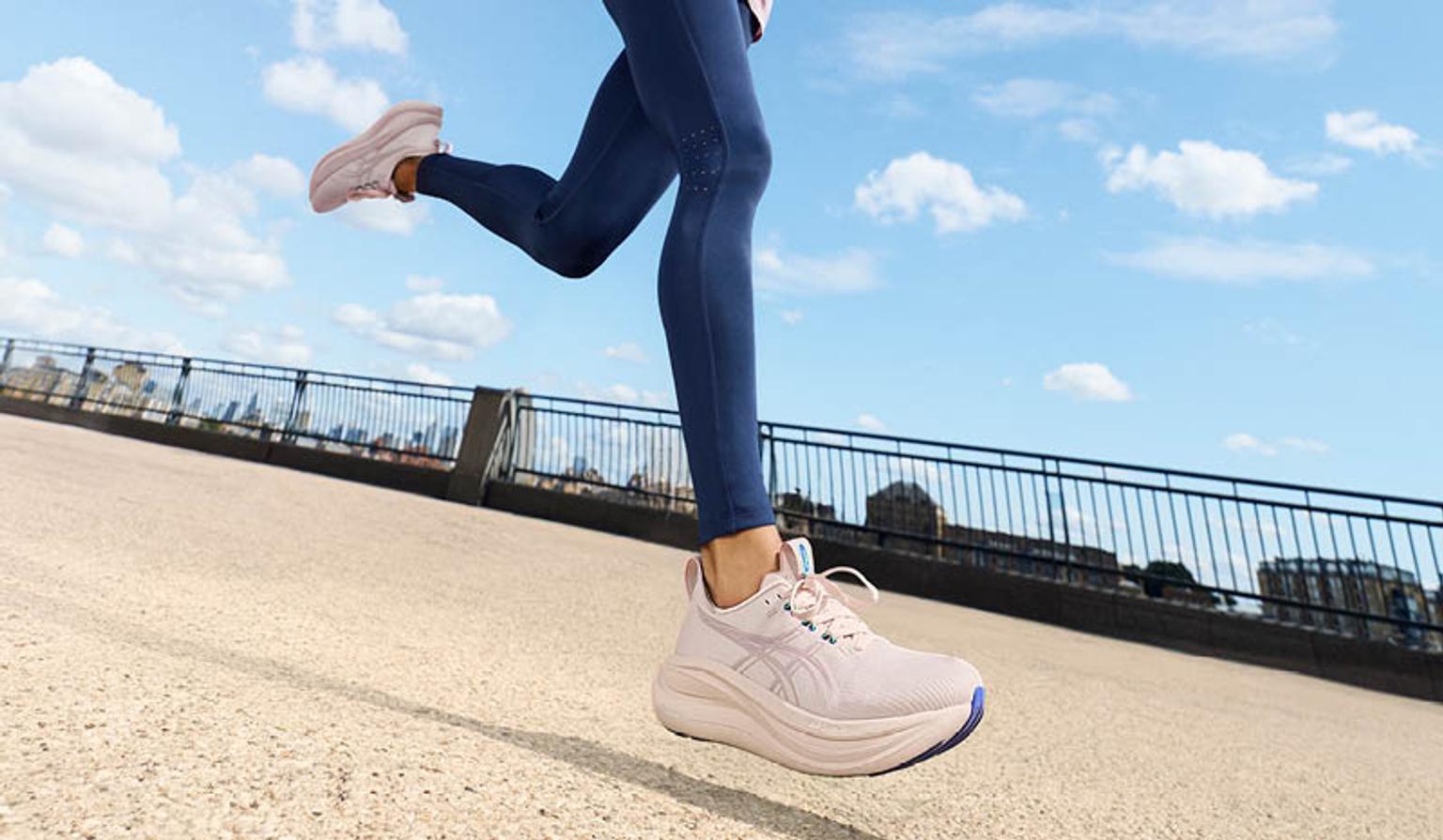 A person's legs in blue leggings and pink running shoes running outdoors.
