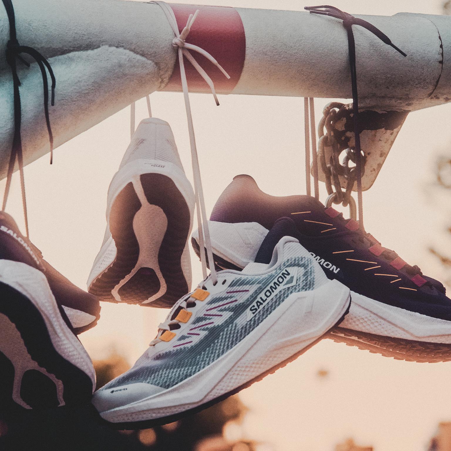 a pair of salomon running shoes hanging from a pole .