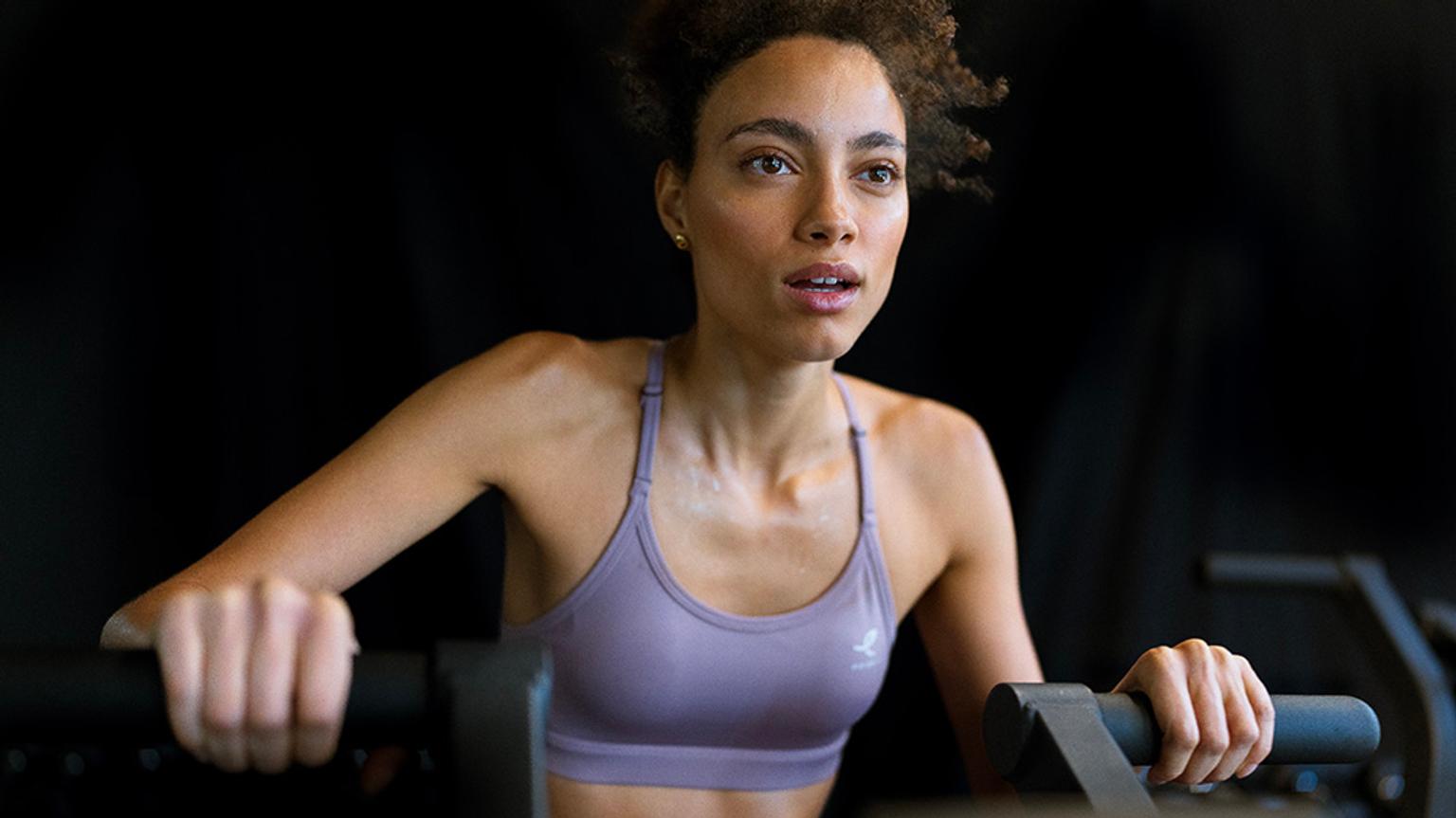 a woman in a purple sports bra is riding a machine in a gym .