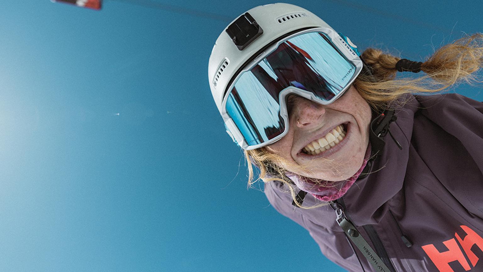 a woman wearing a ski helmet and goggles is smiling .