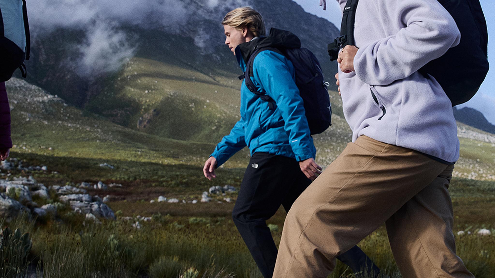 a group of people are hiking in the mountains .