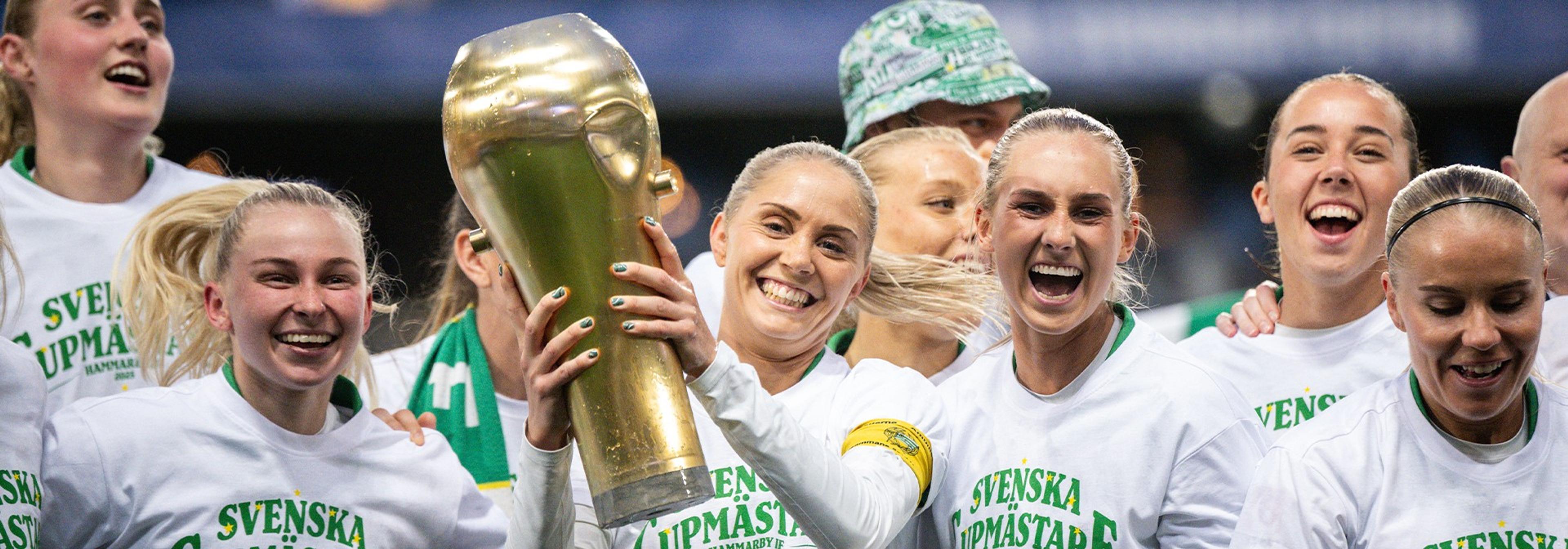Smiling women celebrate with a golden trophy, wearing "Swedish Cup Champions" shirts.