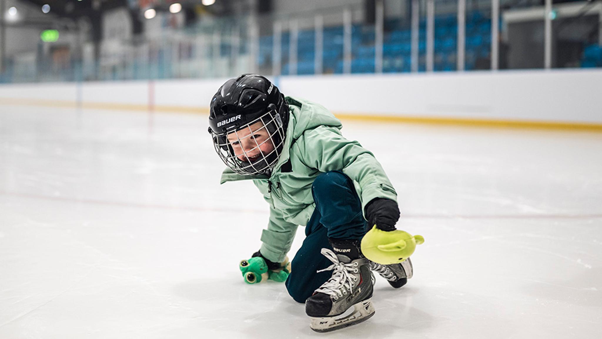 a young boy is playing ice hockey on a rink .