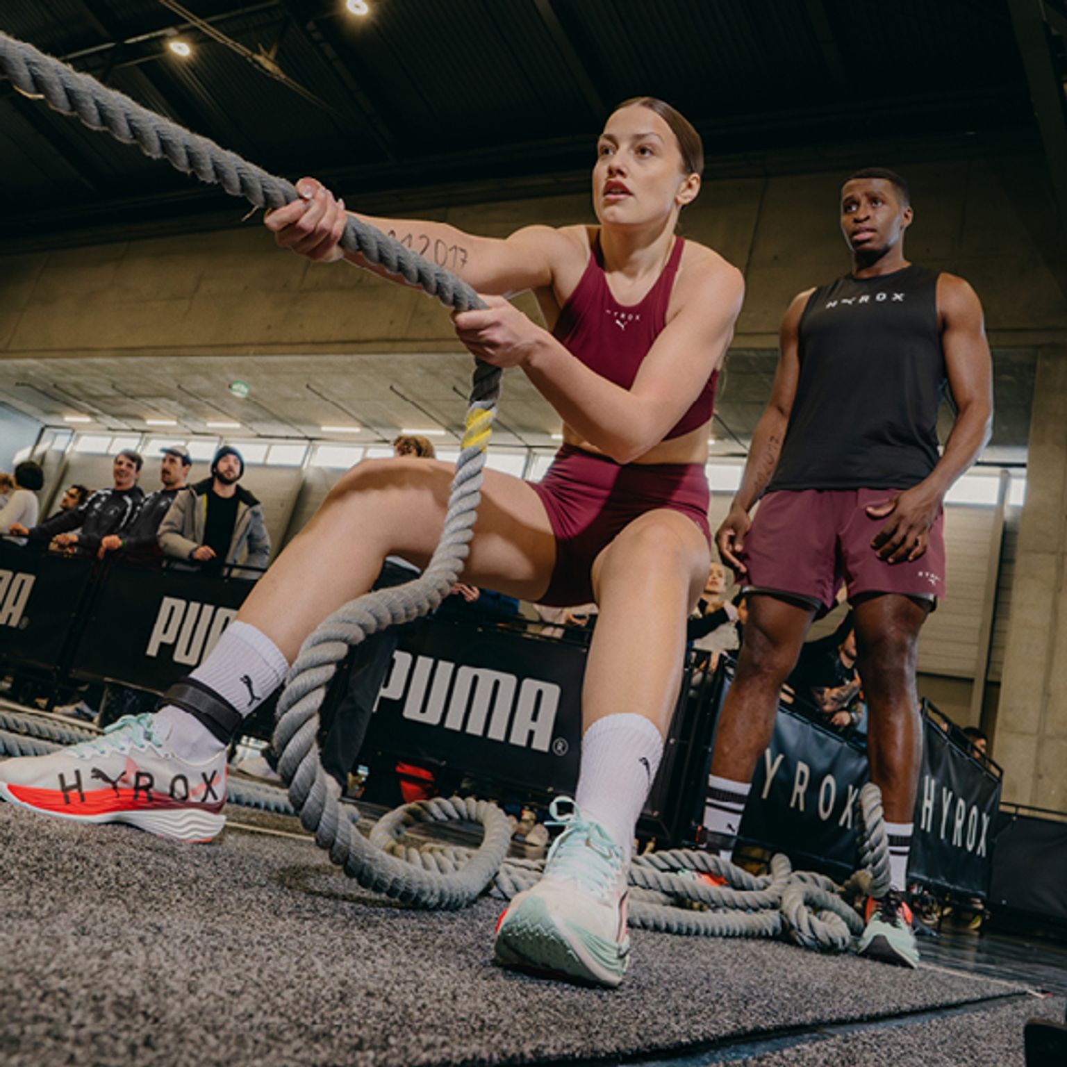 a woman is pulling a rope in a gym while a man watches .