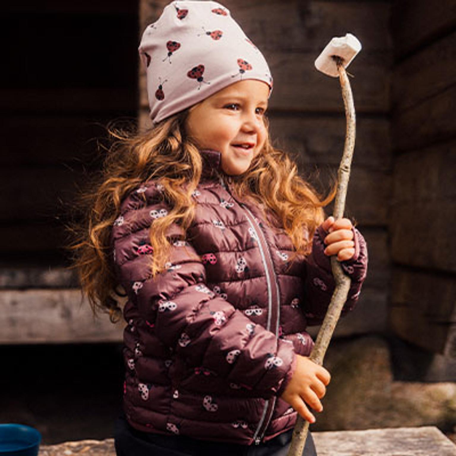 a little girl is holding a stick with a marshmallow on it .