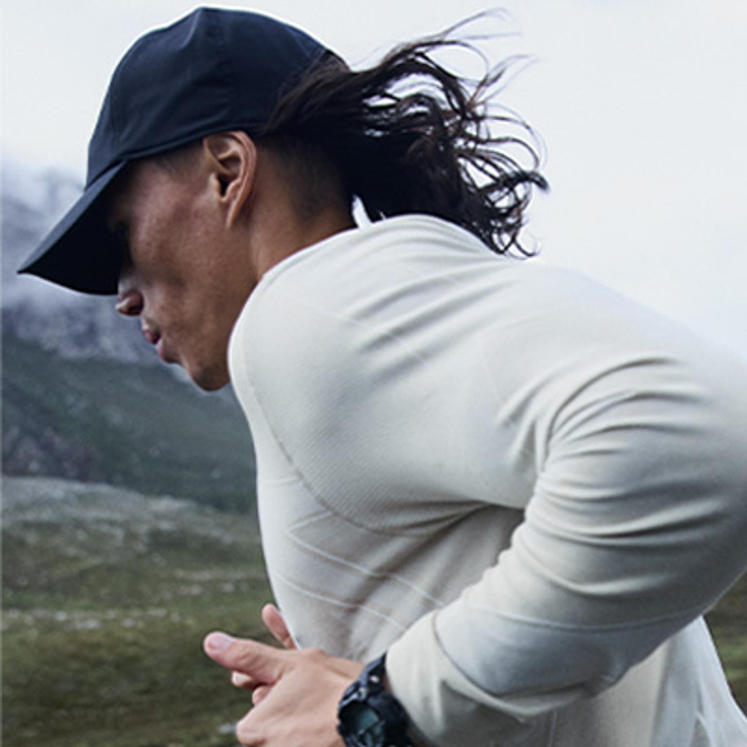 a man wearing a hat and a watch is running in a field .