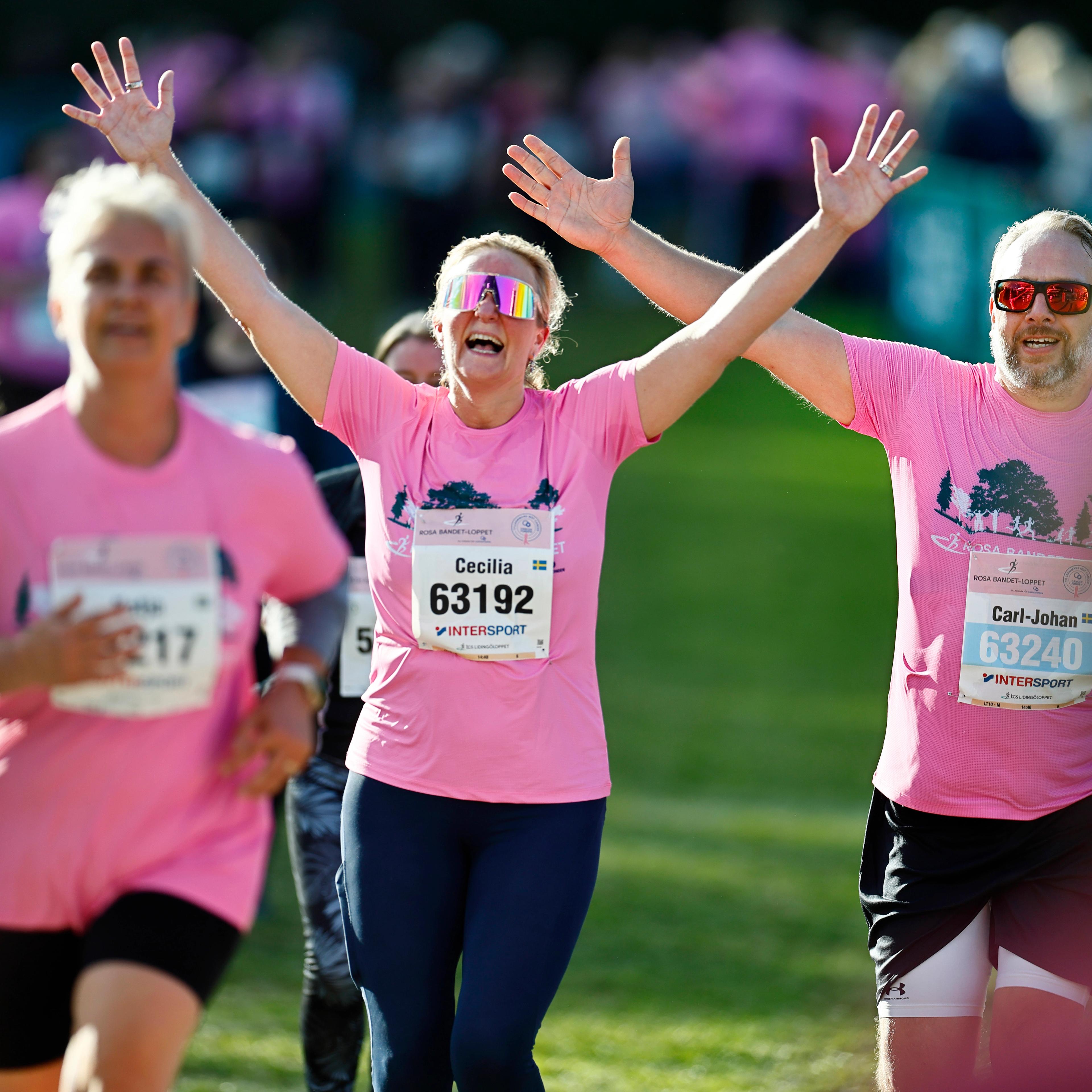 a group of people in pink shirts are running in a race .