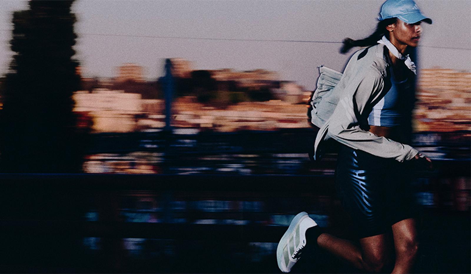 A person in athletic wear running with a blurred city background.