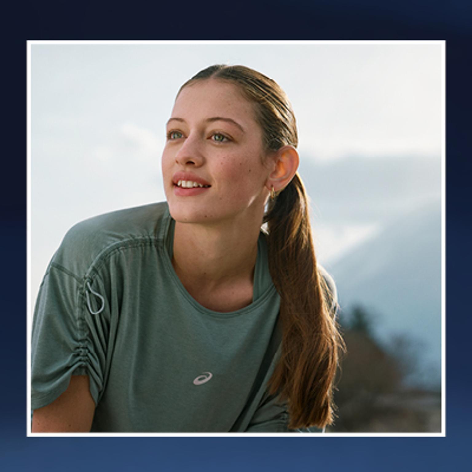 a woman is wearing a green t-shirt and a ponytail .