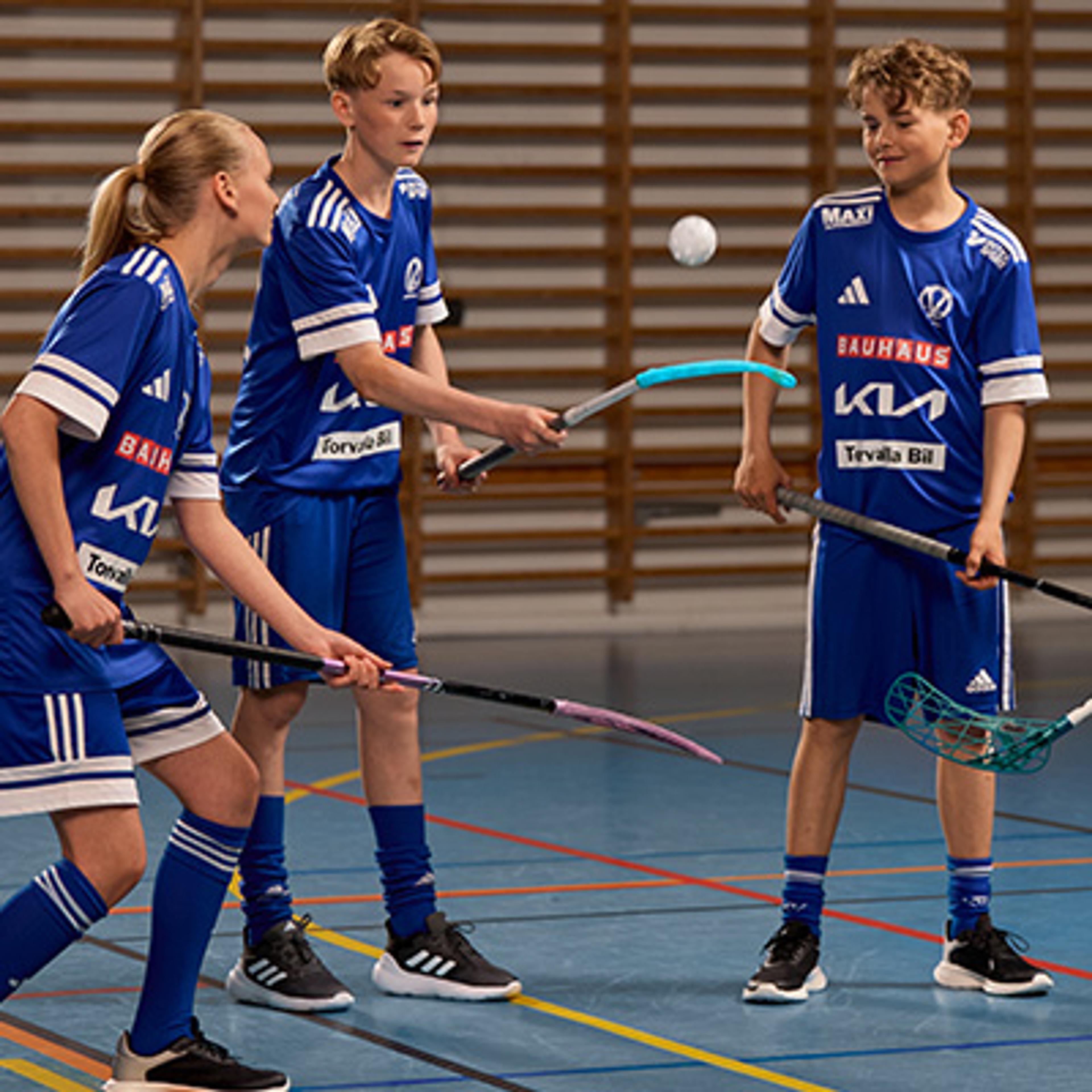 a floorball stick , shoes , glasses , and a ball are on a blue floor .