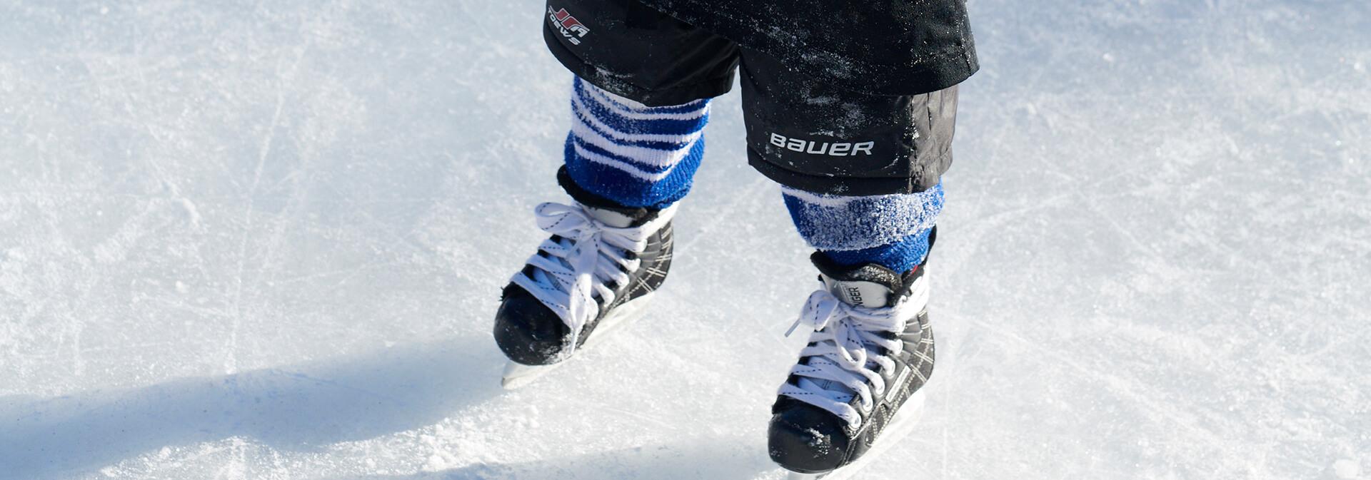 Ett barn står på isen med skridskor