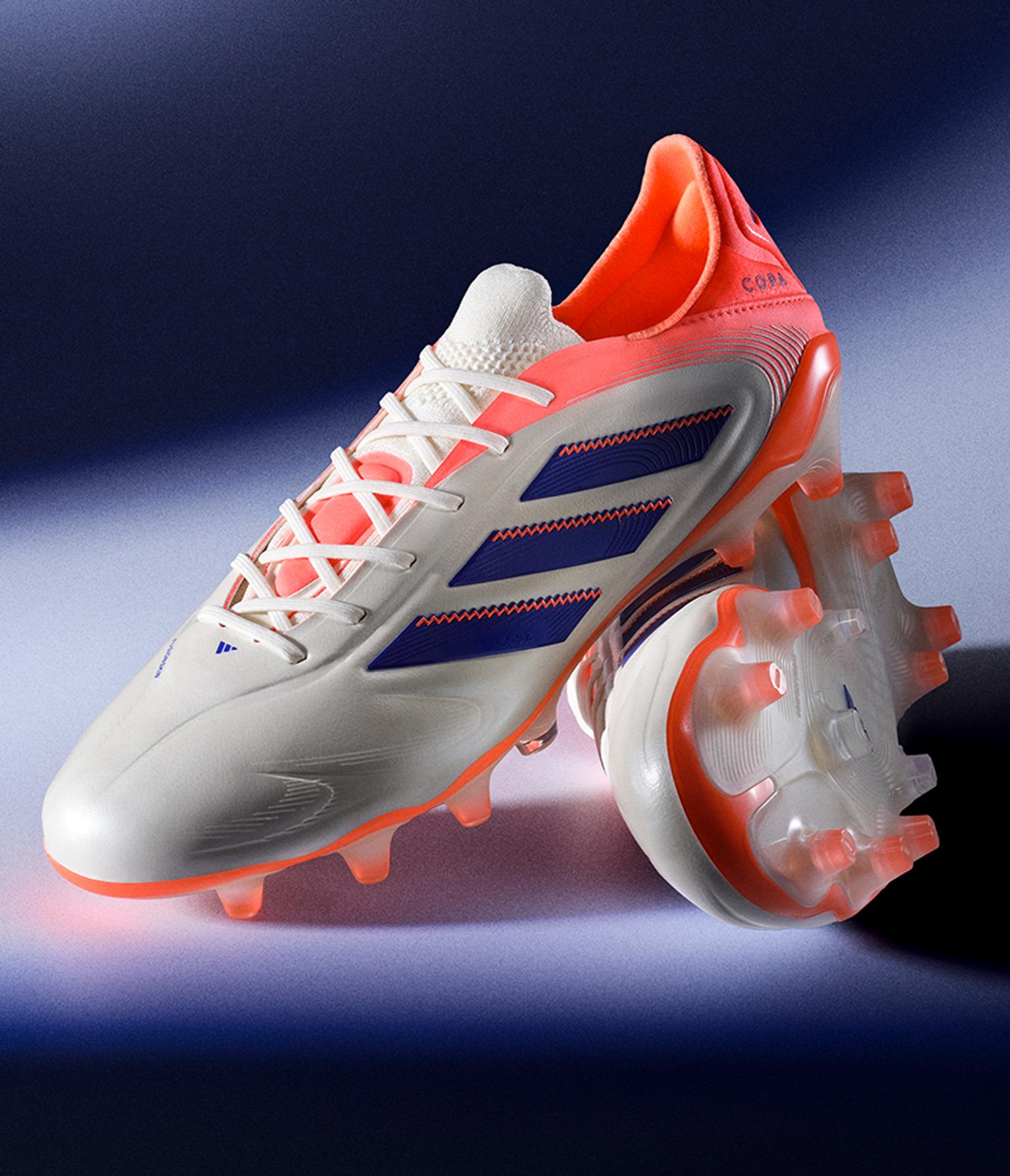 a pair of white and orange adidas soccer cleats