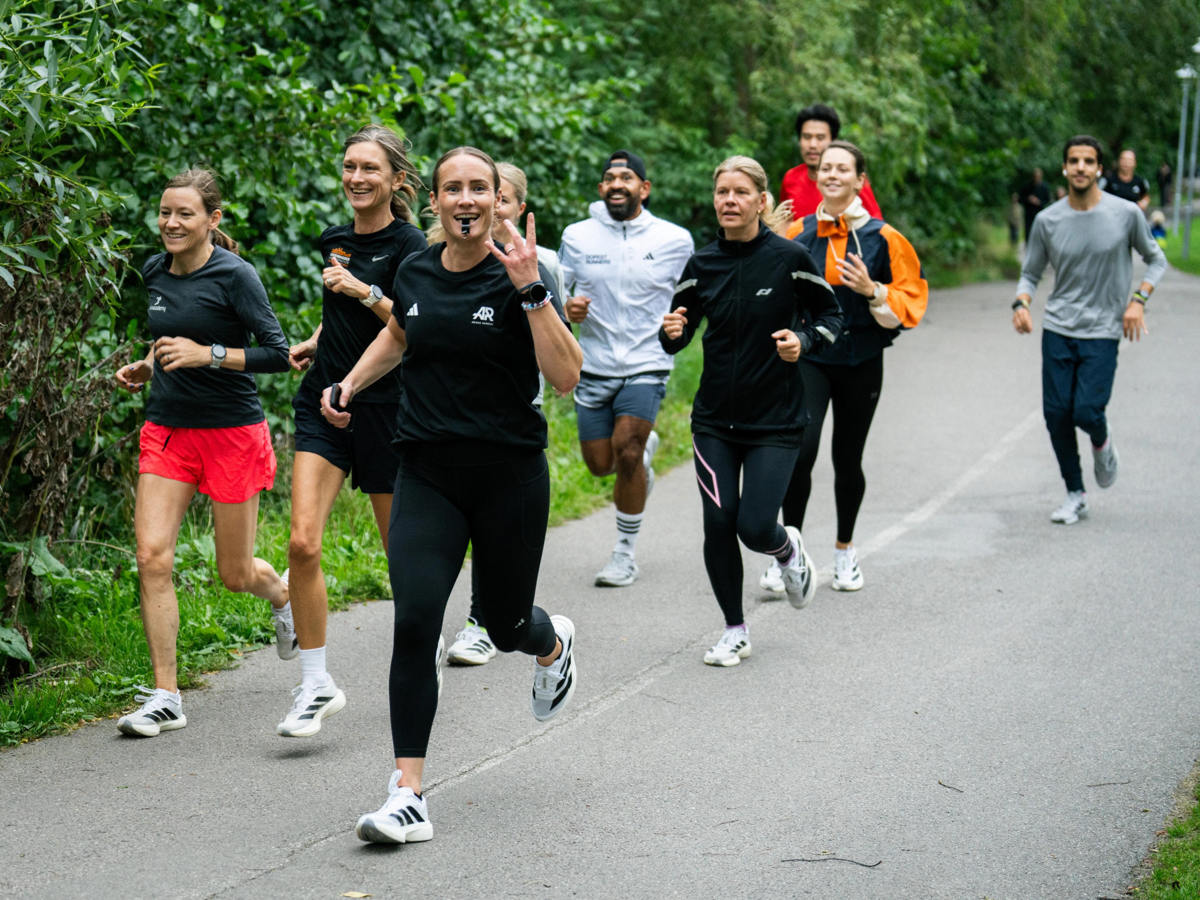 a group of people are running down a path in a park .