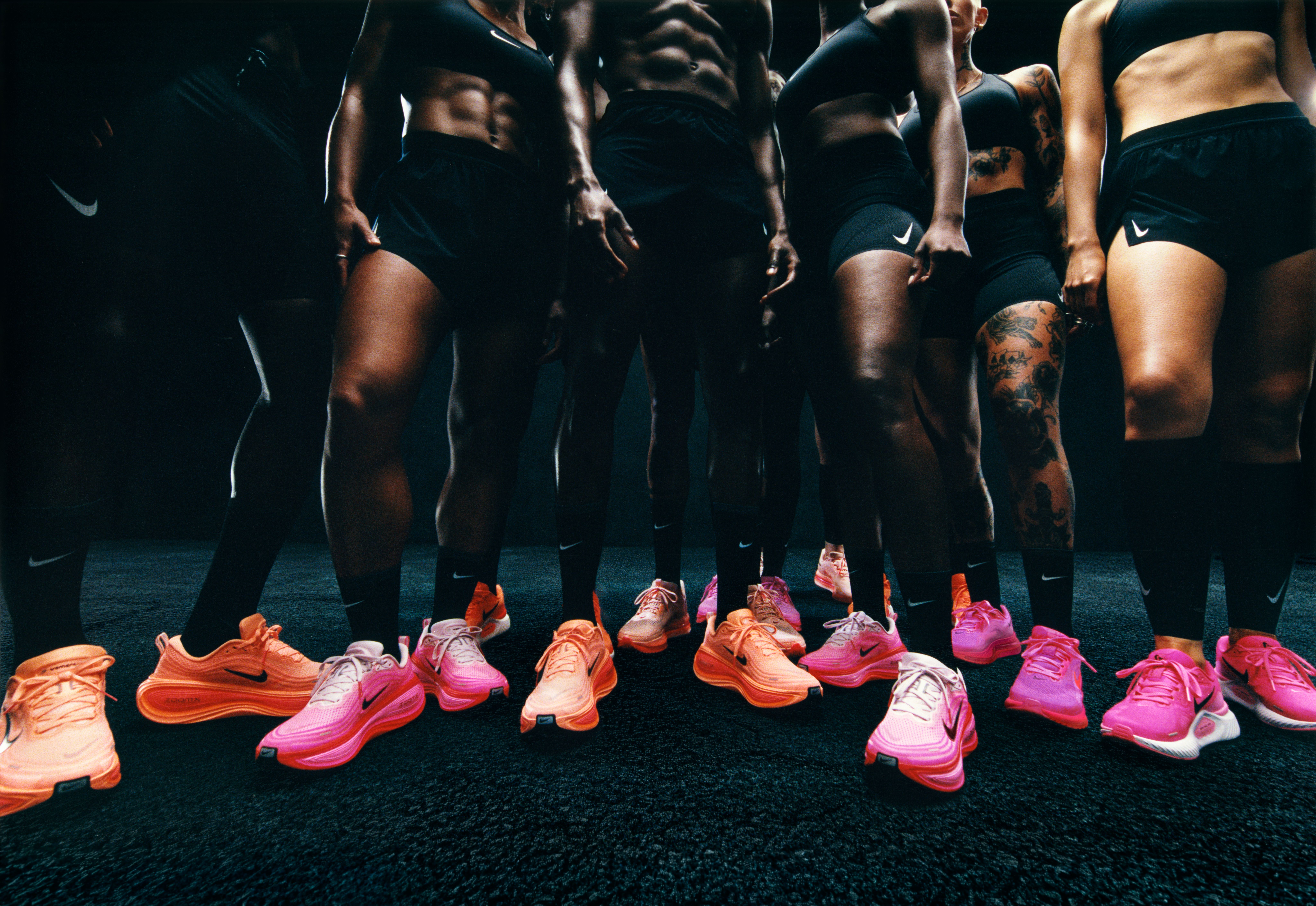 a group of people are standing next to each other wearing pink nike shoes .