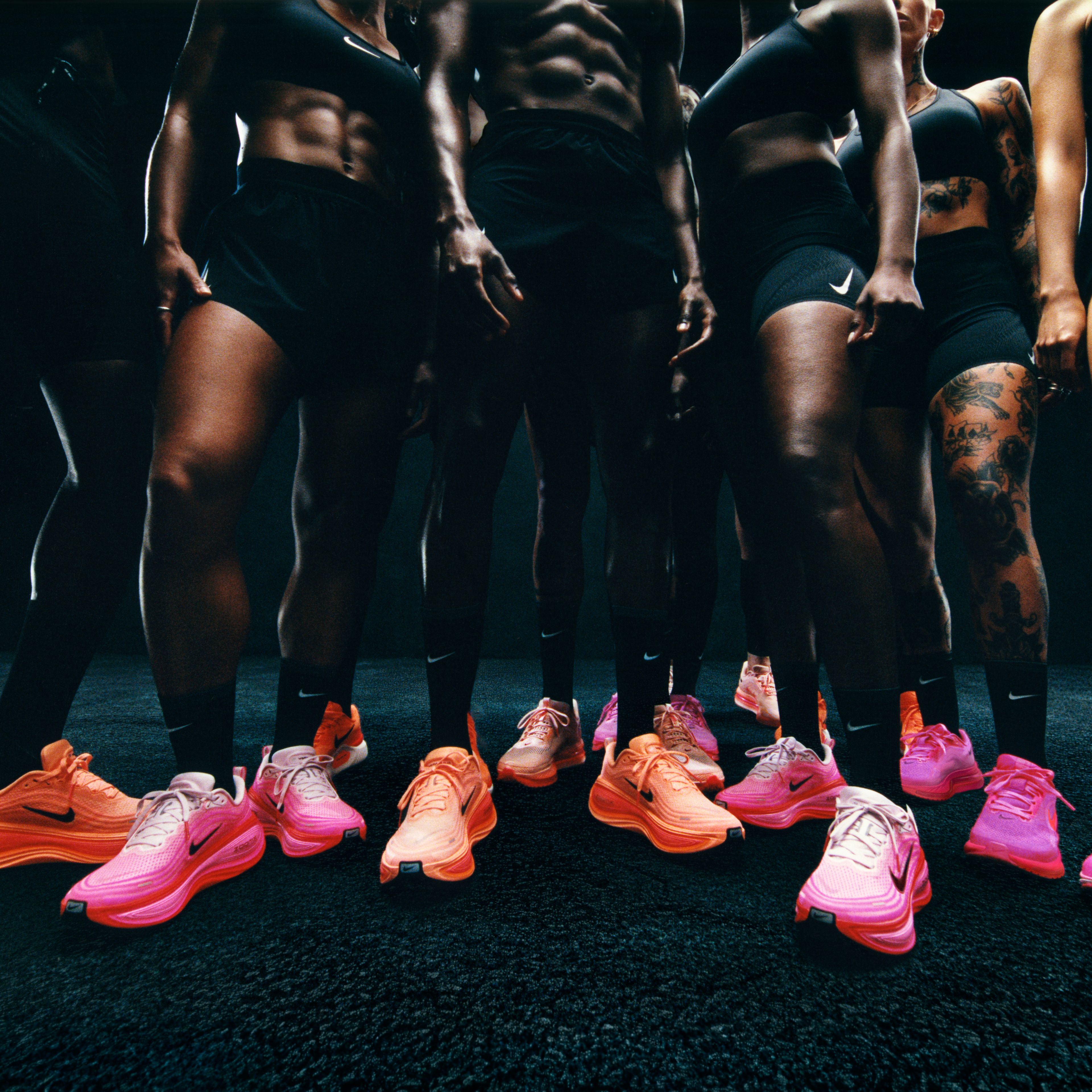 a group of people are standing next to each other wearing pink nike shoes .
