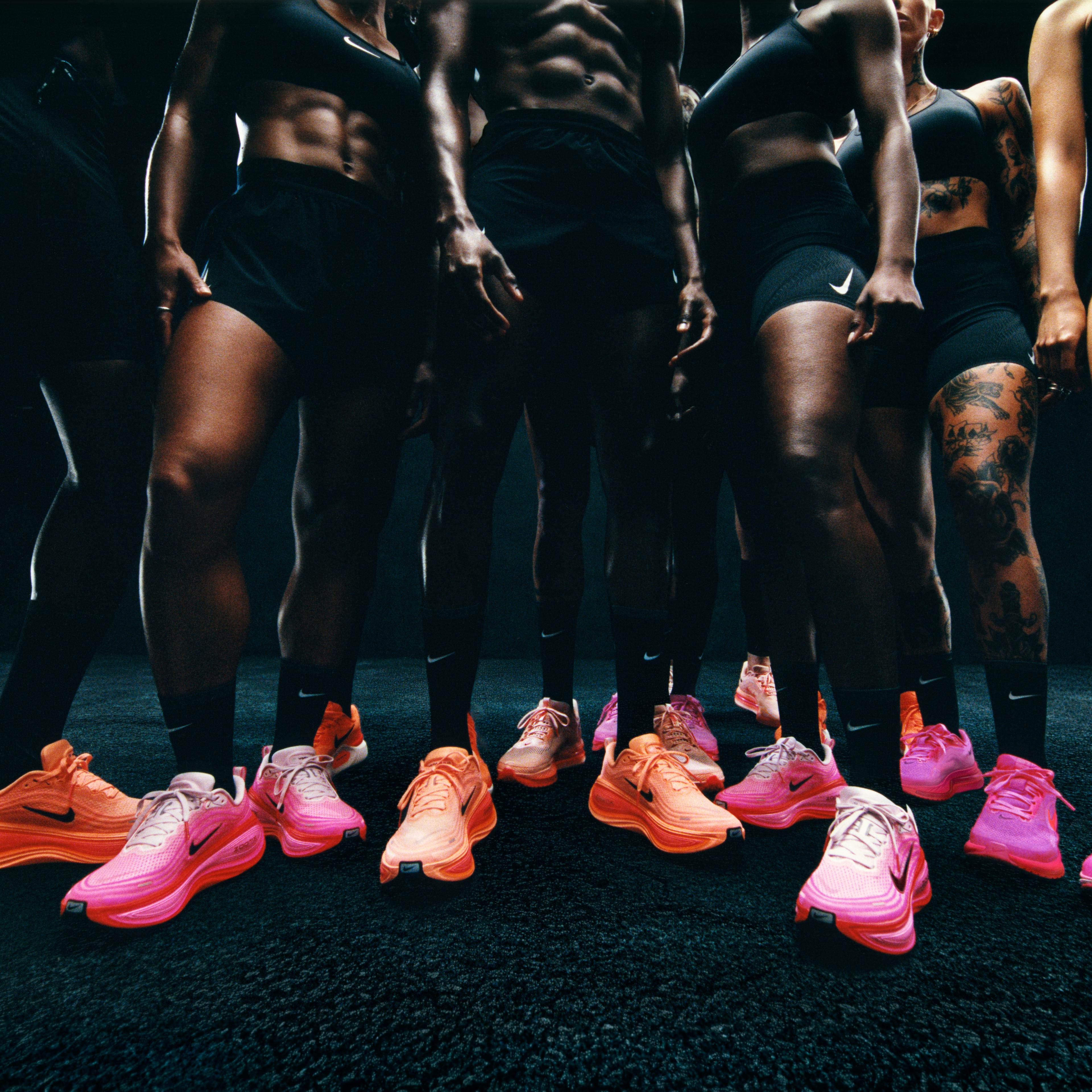 a group of people are standing next to each other wearing pink nike shoes .