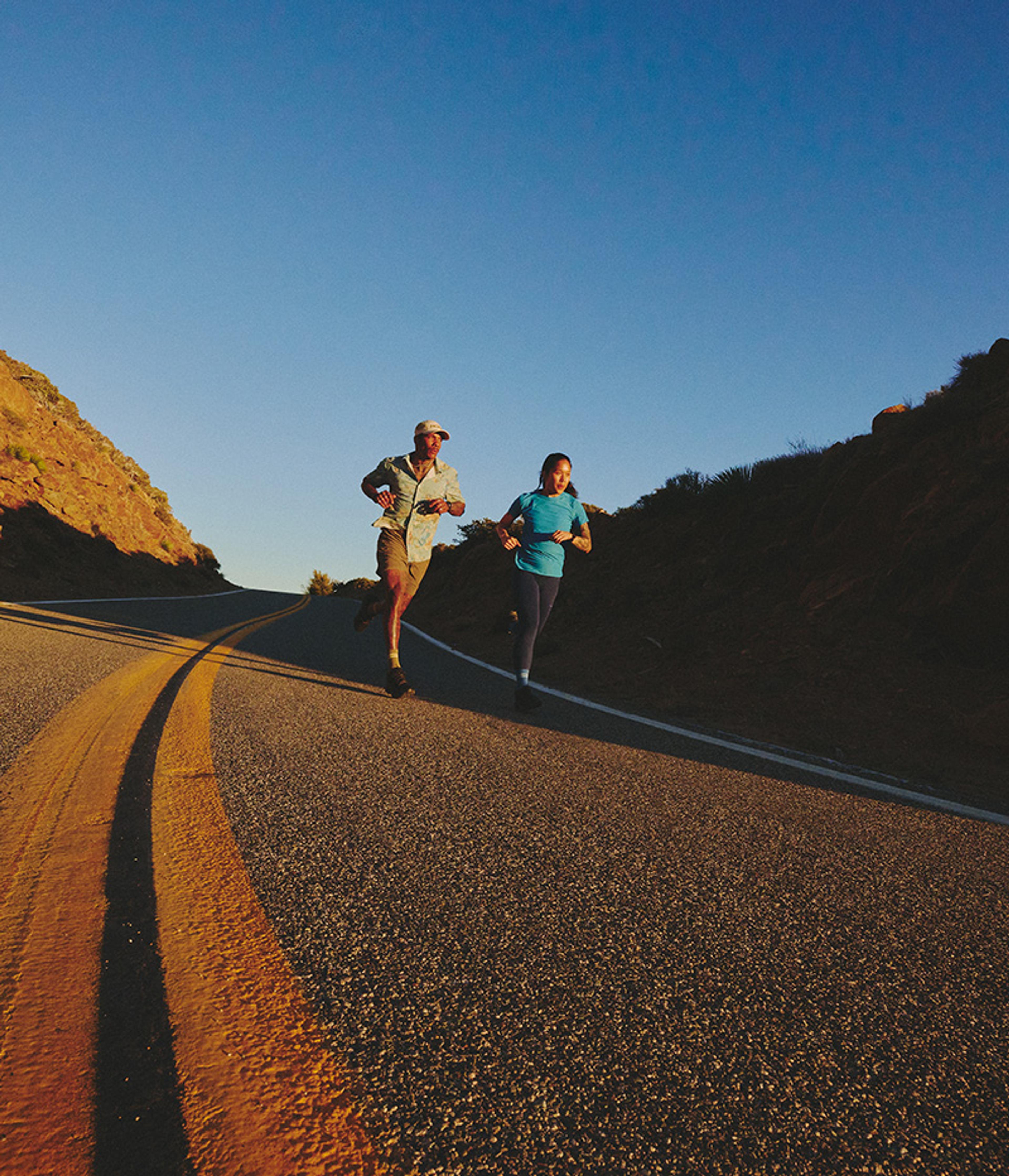 a man and a woman are running down a road .