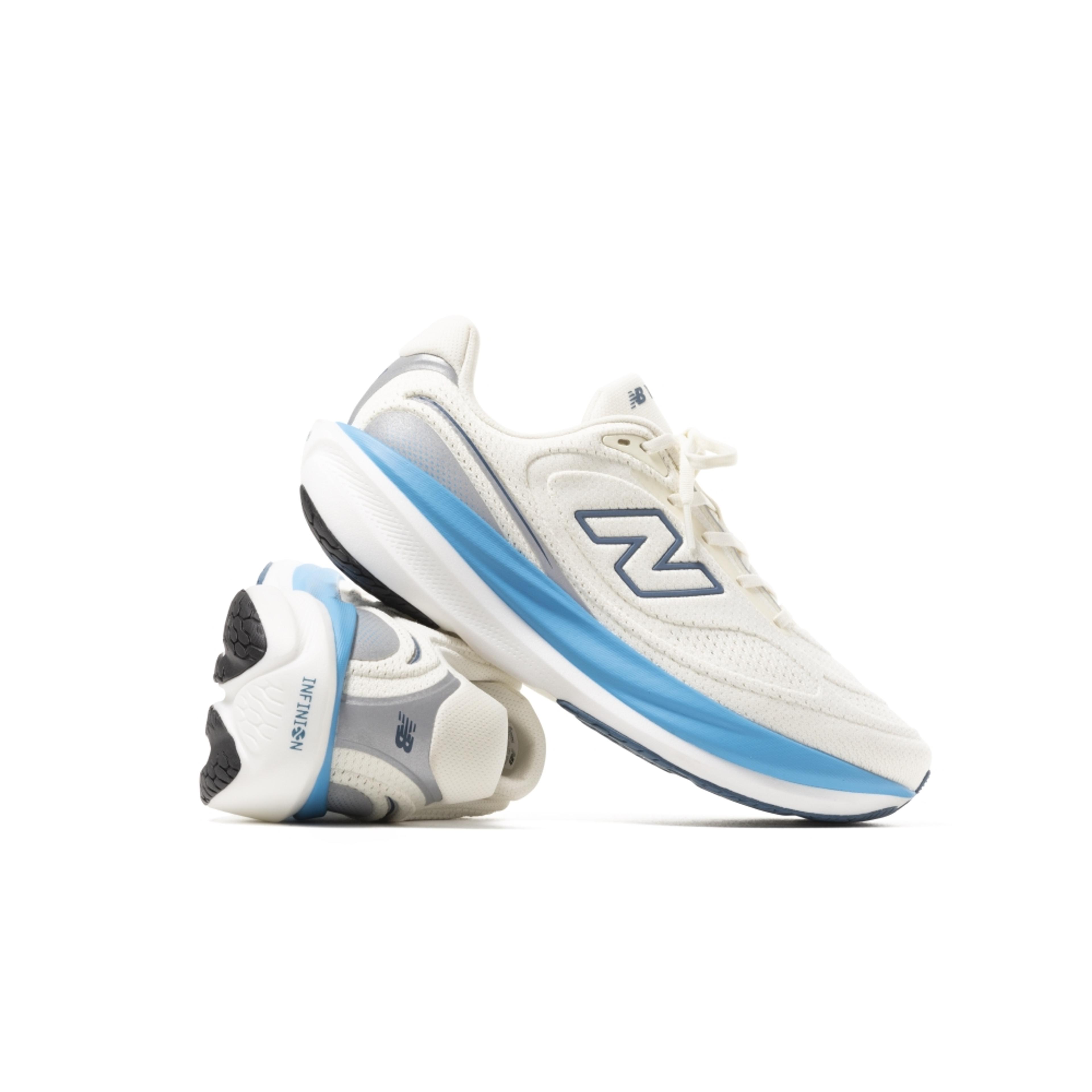 Pair of off-white New Balance sneakers with light blue and grey accents, one upright and one on its side.