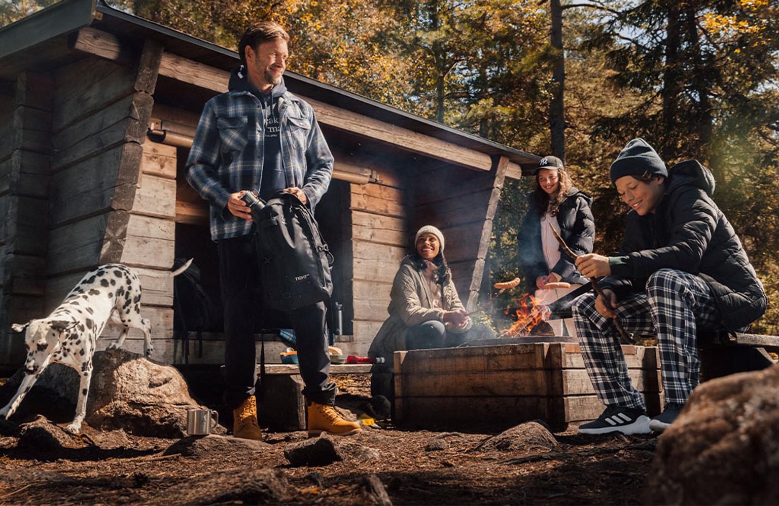 a group of people are sitting around a campfire in the woods .