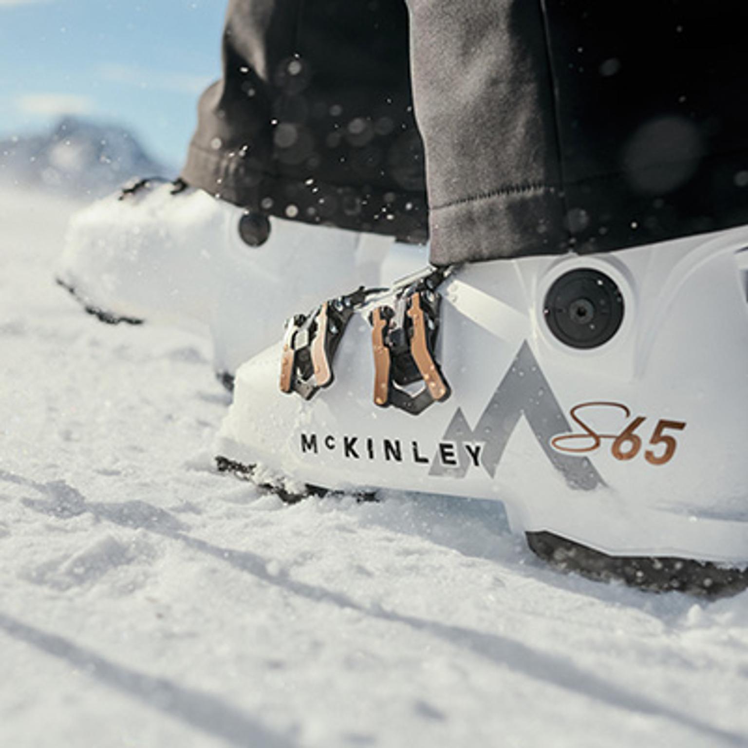 White McKinley S65 ski boots standing in snow.