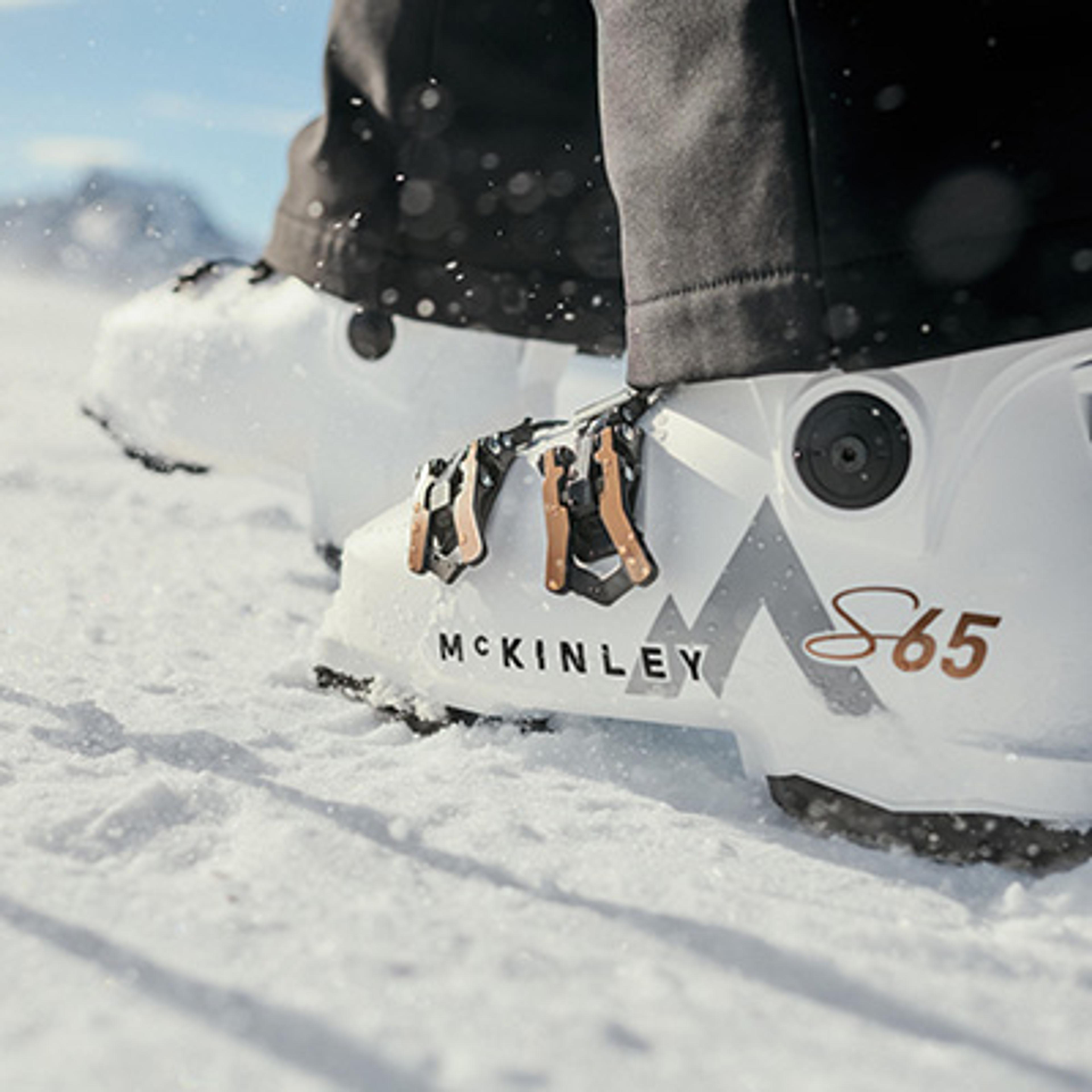 White McKinley S65 ski boots standing in snow.