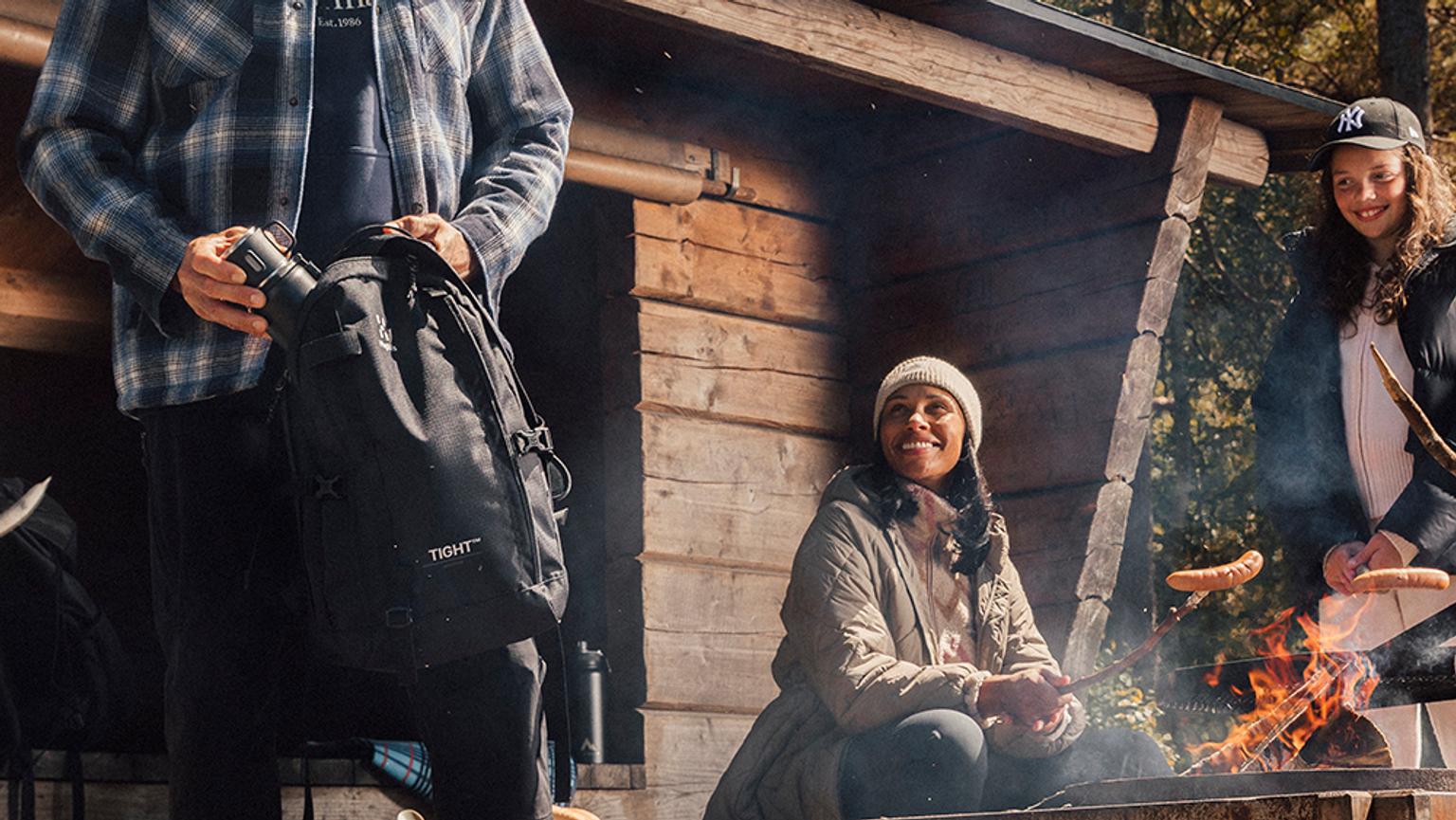 a group of people are eating outside sitting around a campfire .