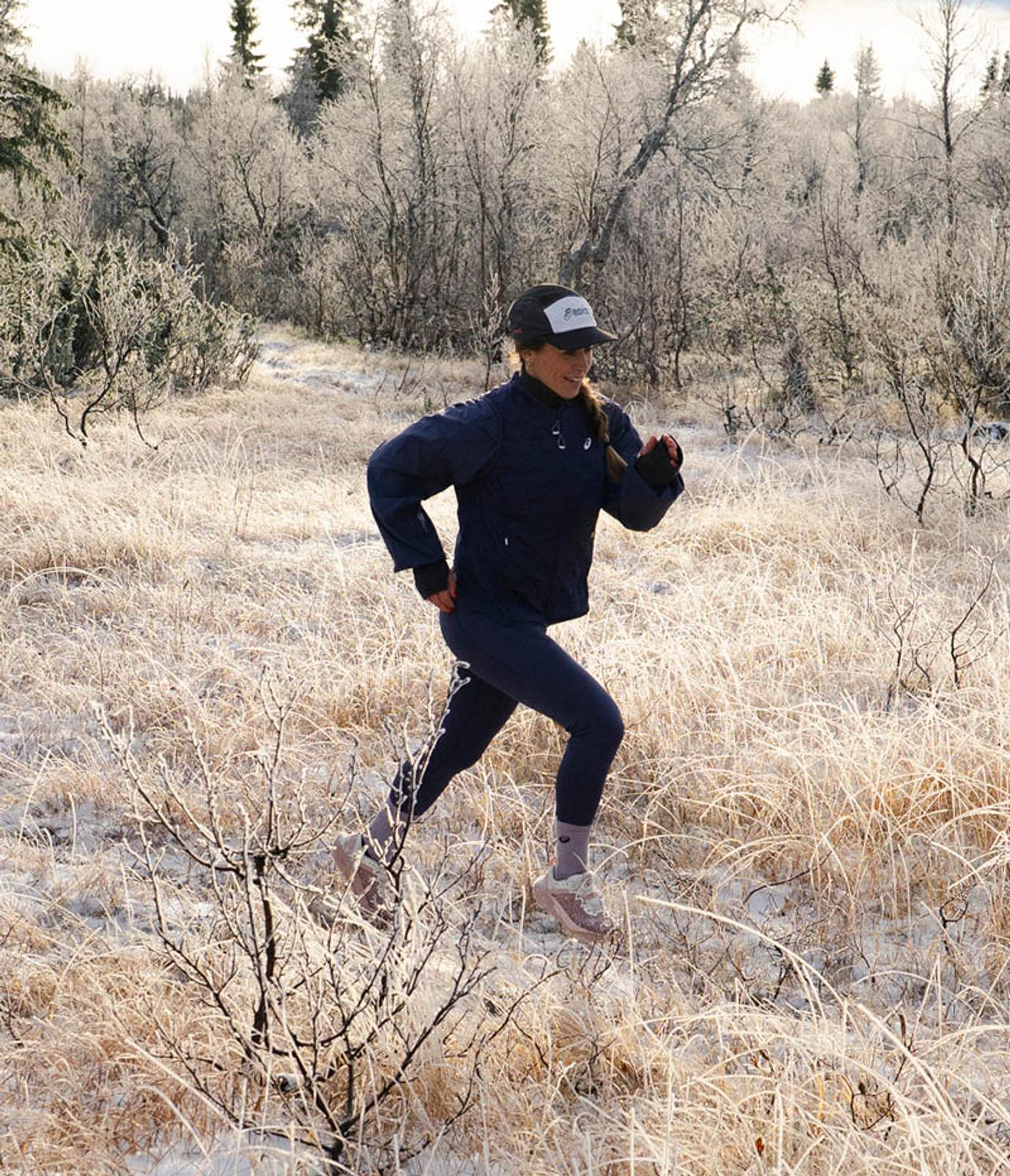 A woman running in a frosted winter field.