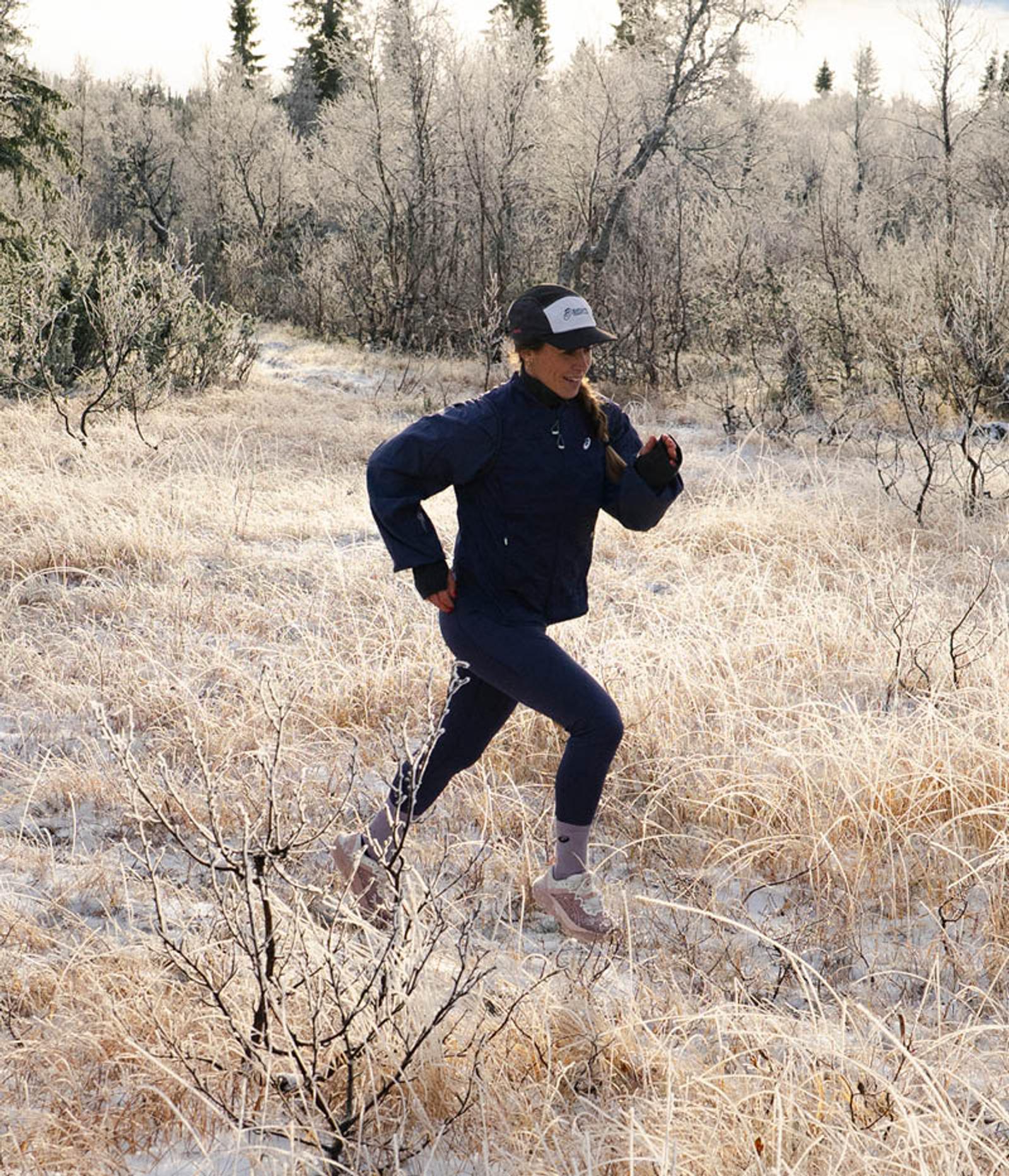 A woman running in a frosted winter field.