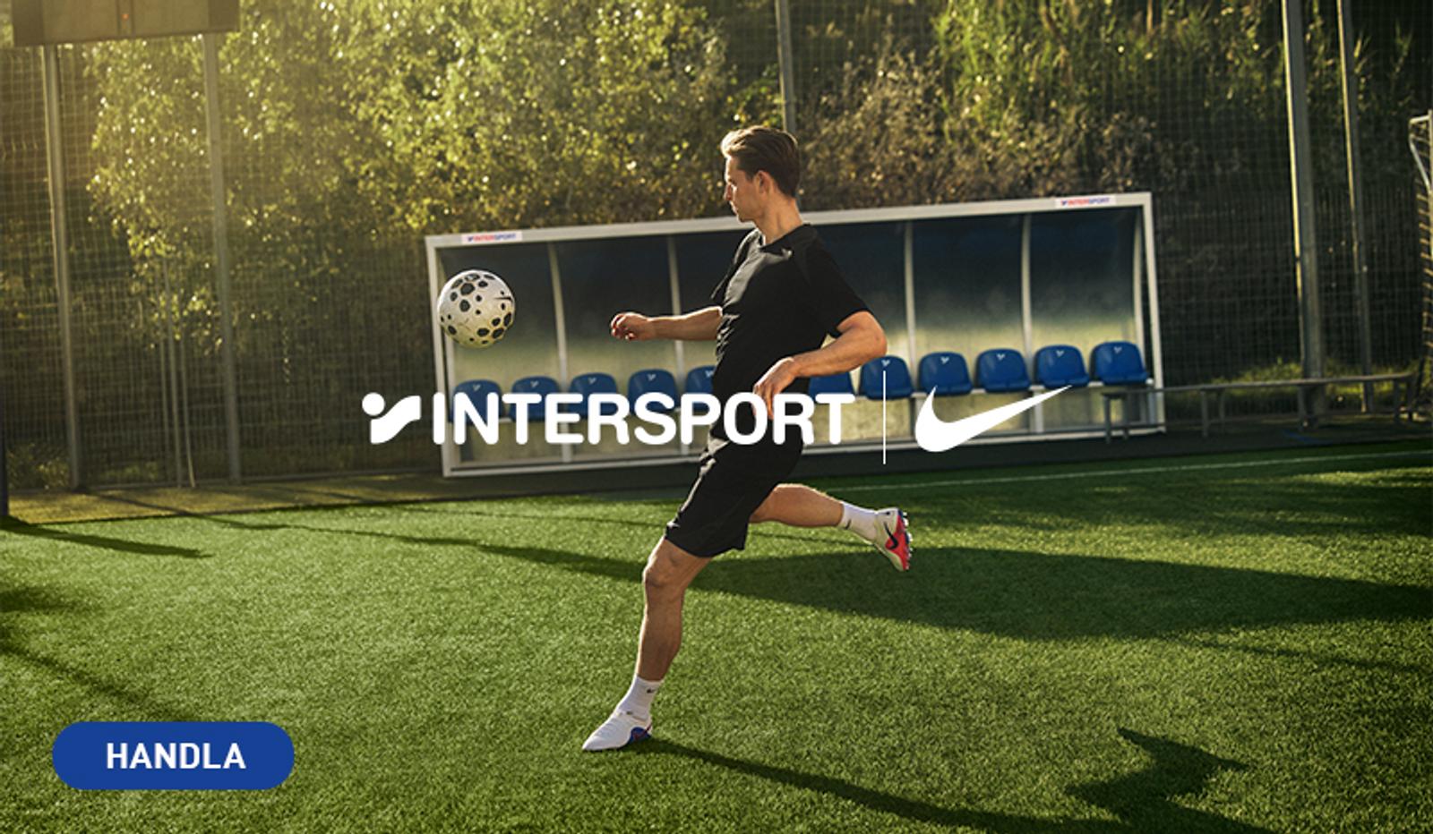 A man in a black kit kicks a soccer ball on a green turf field, with Intersport and Nike logos overlaid, and "HANDLA" in a blue box.