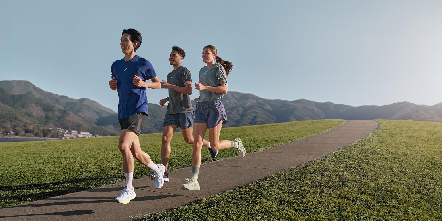 a group of people are running on a path in a park .