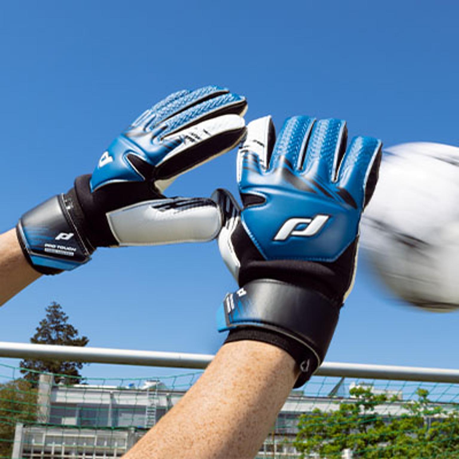 a person wearing a pair of goalie gloves is reaching for a soccer ball .