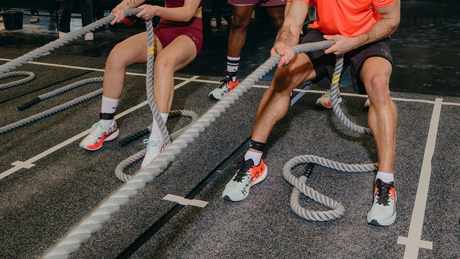 A man and a woman pulling a thick rope during a gym workout.