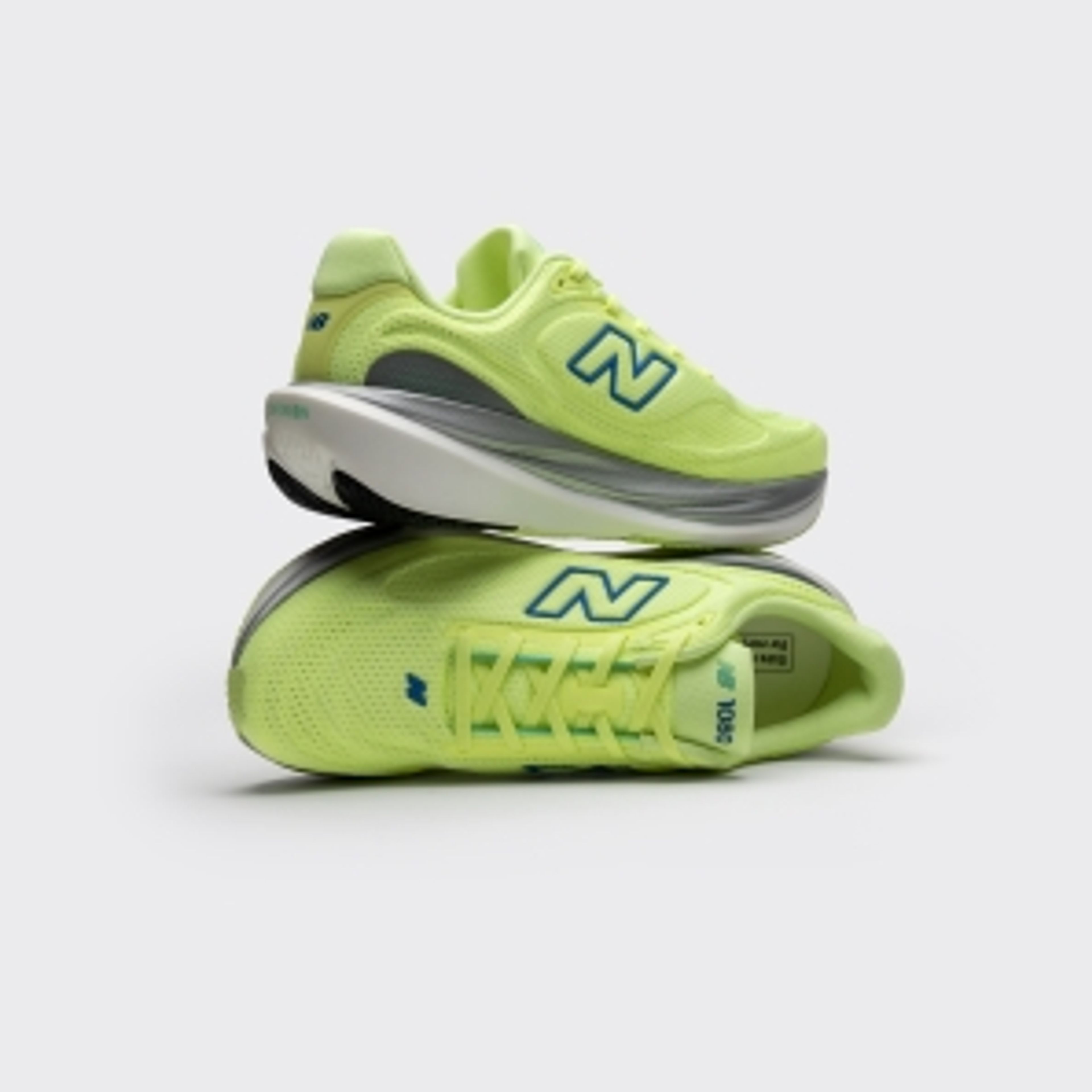 Two vibrant lime green New Balance sneakers with blue 'N' logos, one stacked on top of the other.
