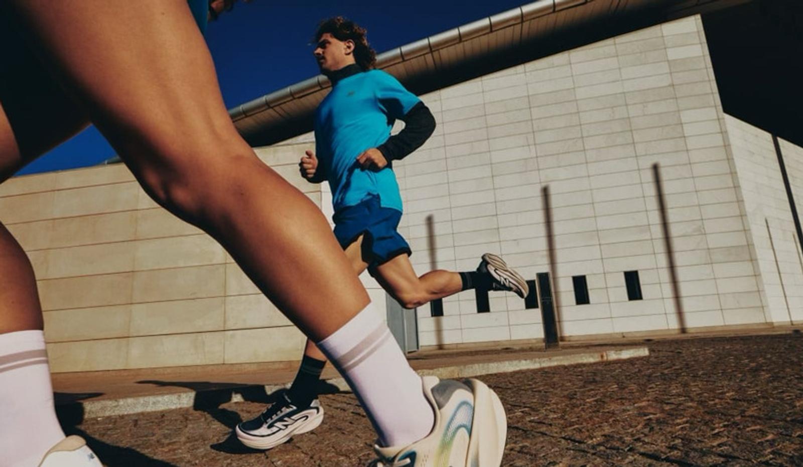 Two athletes running past a modern building.
