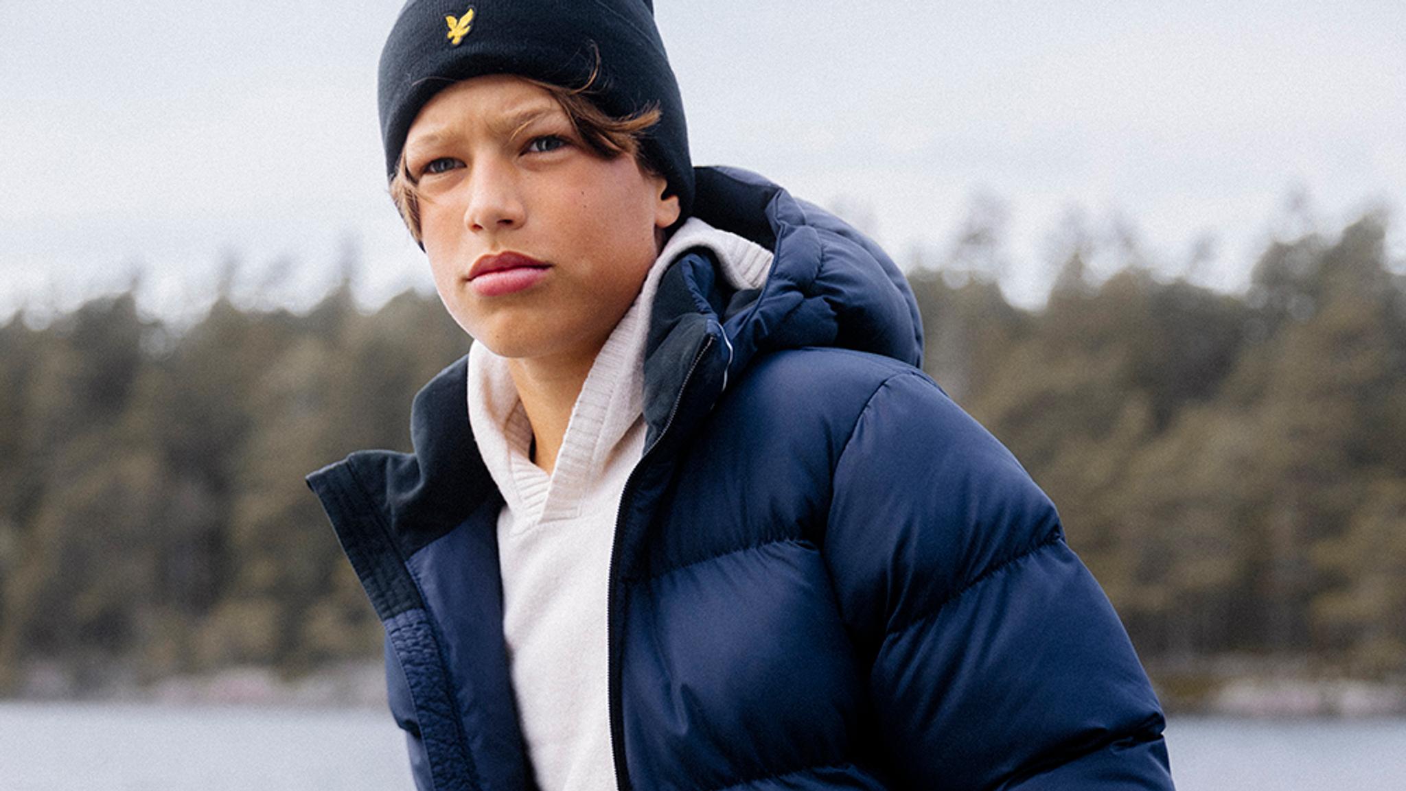 a young boy wearing a blue jacket and a black hat .
