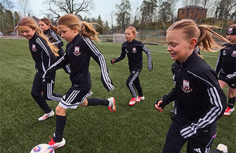 a group of young girls are playing soccer on a field .