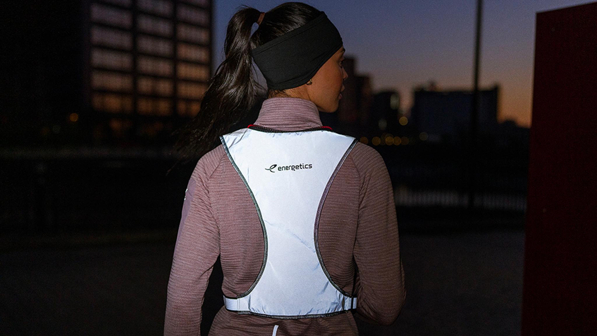 a woman is wearing a reflective vest and headband .