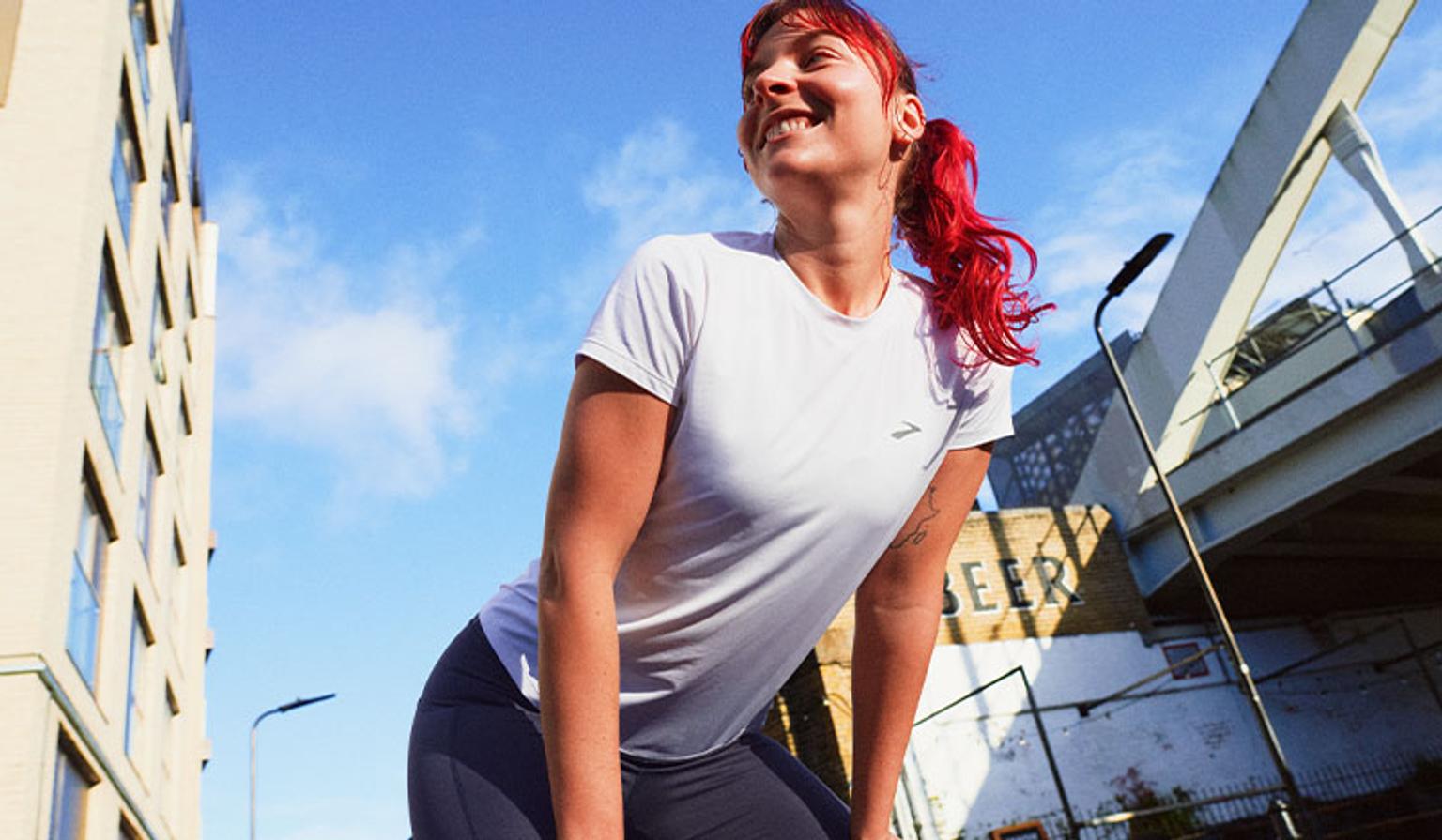 a woman with red hair is wearing a white t-shirt and black pants .